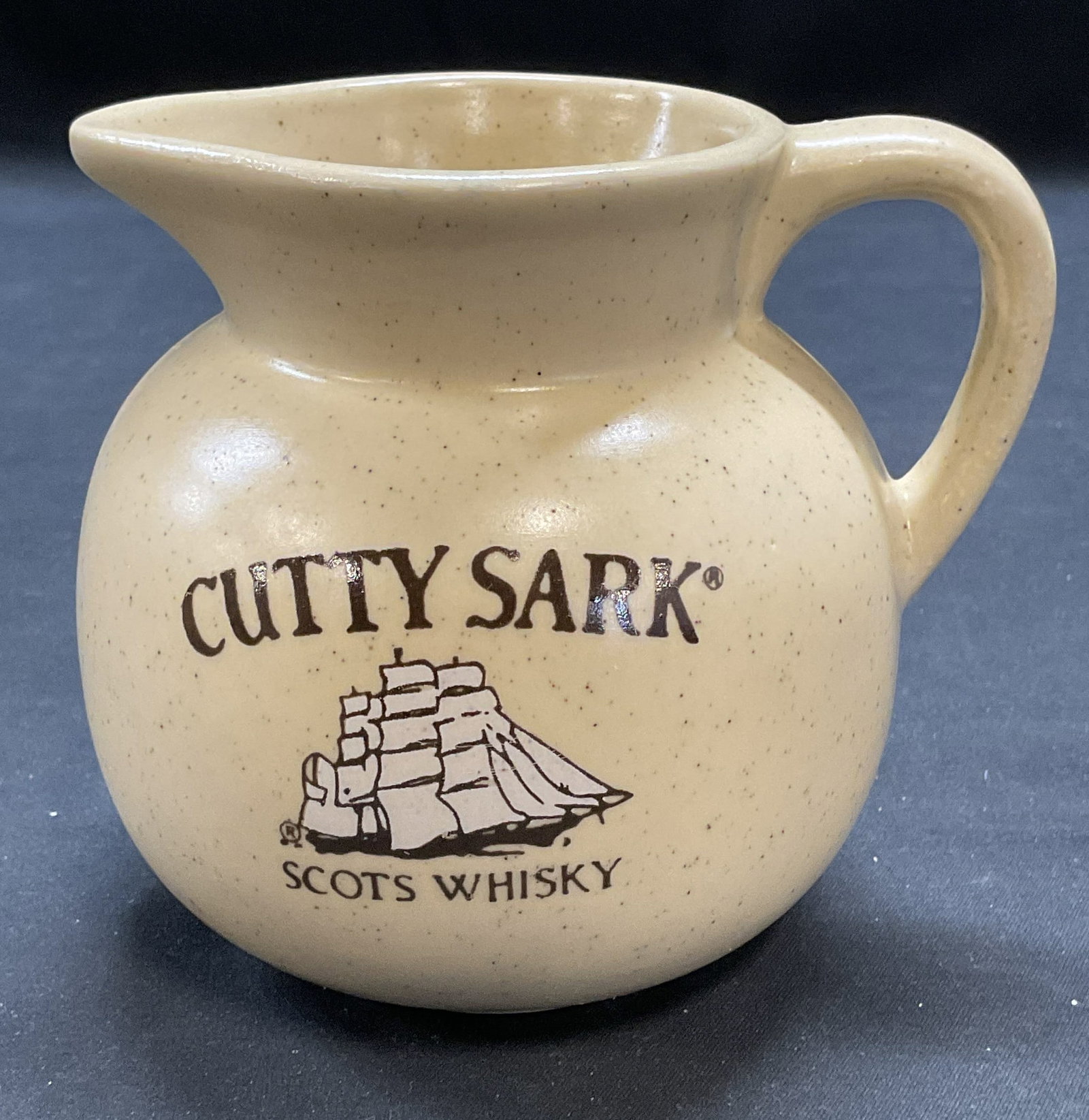 Cutty Sark Scots Whisky Ceramic Pitcher: Ceramic pitcher with Cutty Sark Scots Whisky logo design. Measures approx. 4.5 x 3.75 x 4.25 inches. Some wear including scratching observed. Cutty sark, cutty sark scots whisky, cutty sark pitcher, c