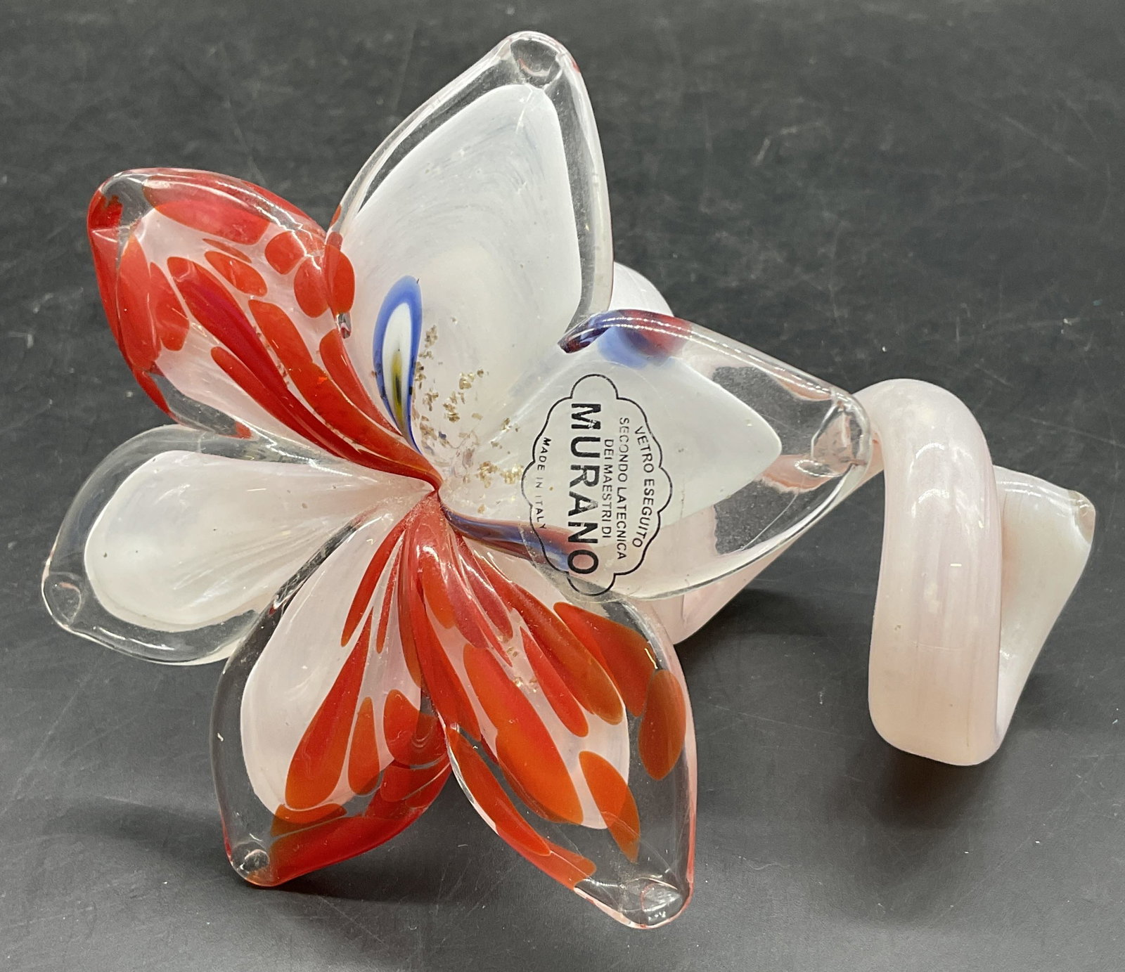MURANO VETRO ESEGUITO Art Glass Flower, Italy: MURANO VETRO ESEGUITO Art Glass Flower. Red and white hues primarily with ascents of blue and green. Sticker reads MURANO VETRO ESEGUITO MADE IN ITALY. Measures approx. 3.5H x 4W in. Rough edge to ste