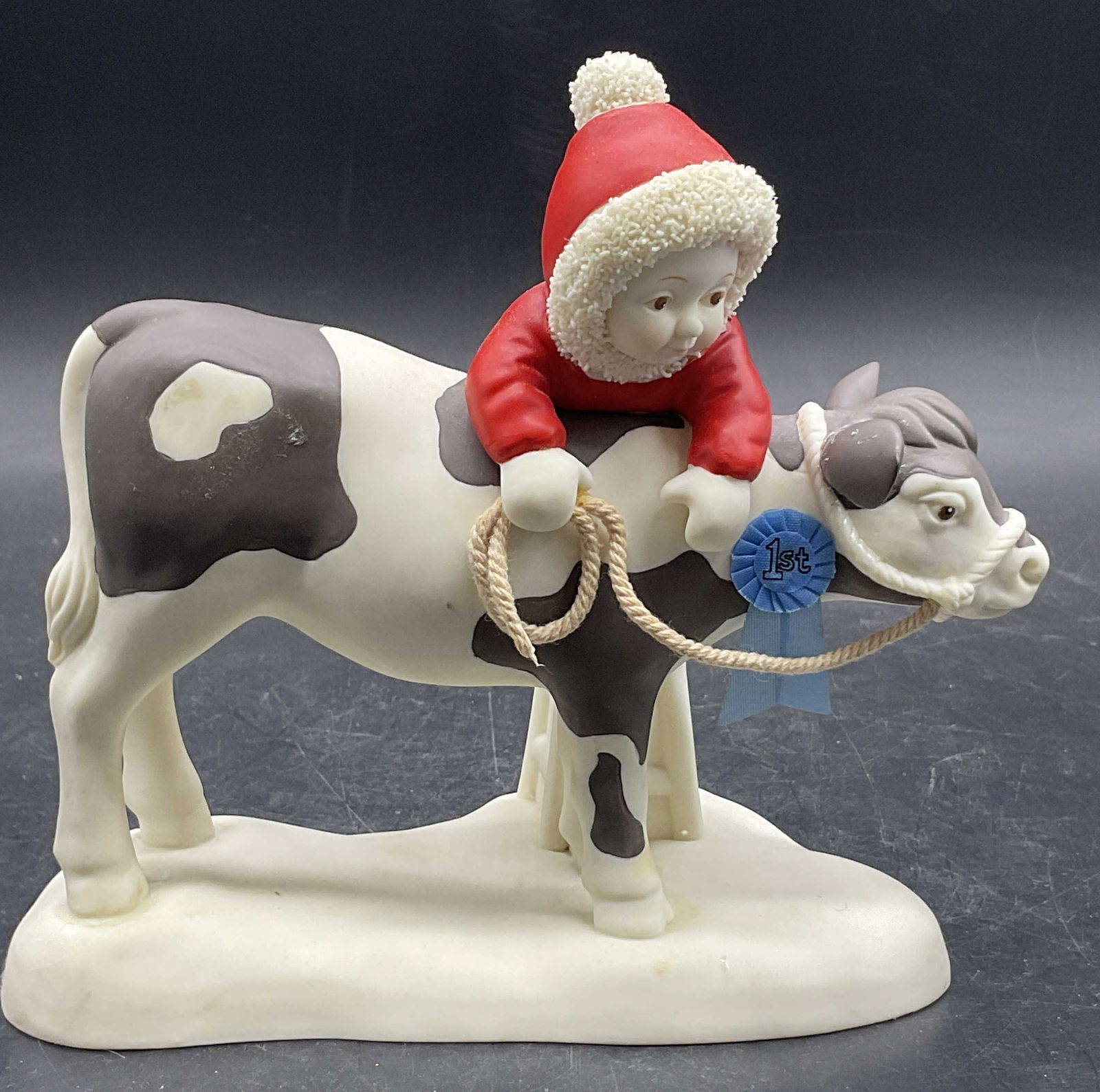 2002 DEPARTMENT 56 BEST OF SHOW Ceramic Figural: 2002 DEPARTMENT 56 BEST OF SHOW Ceramic Snowbaby / Snowbabies Figural. The snowbaby is depicted riding atop a cow. Fabric rope and pin accent. Underside reads 2002 DEPARTMENT 56 BEST OF SHOW. Measures
