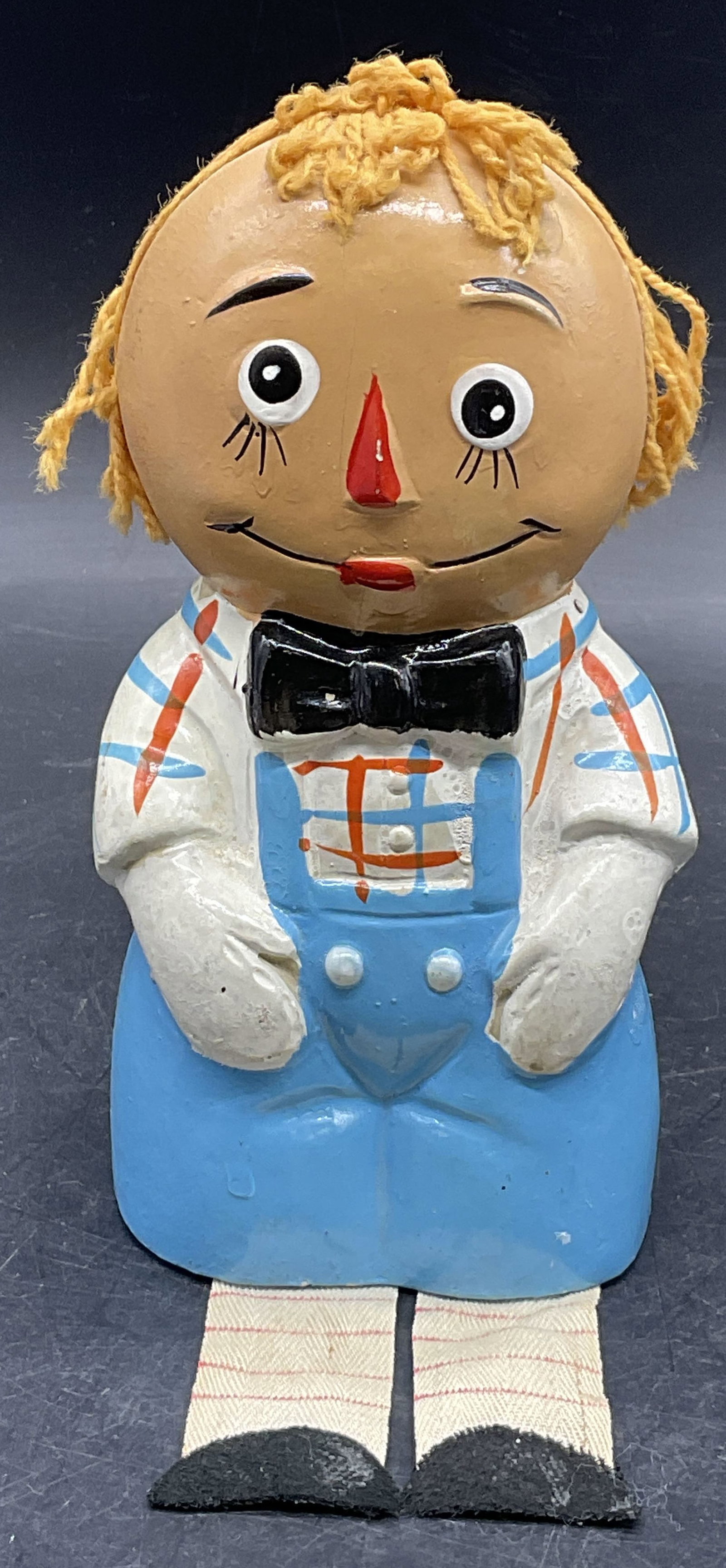 Vintage Hand Painted Raggedy Andy Coin Bank: Vintage Hand Painted Raggedy Andy Coin Bank. Crafted from composite materials with yarn hair and cloth legs. Slot to reverse and hole to underside. Losses, discoloration, and surface wear present meas