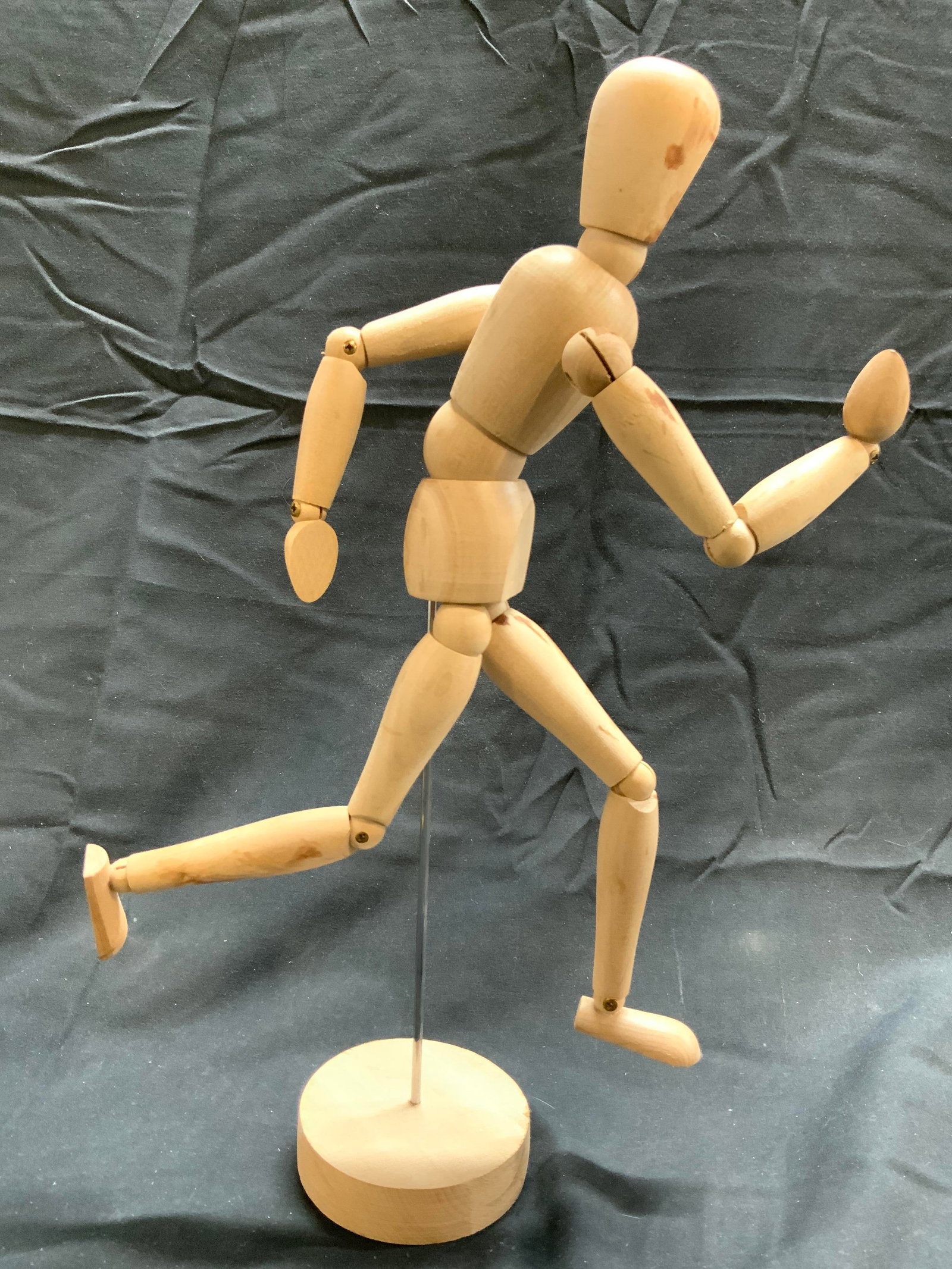 IKEA 13 Inch Wooden Mannequin: Tag on underside reads IKEA. Mannequin is tan toned and wooden. Piece has circular form wooden base. Mannequin is affixed to base with metal rod. Piece measures approximately 13 inches tall with base 