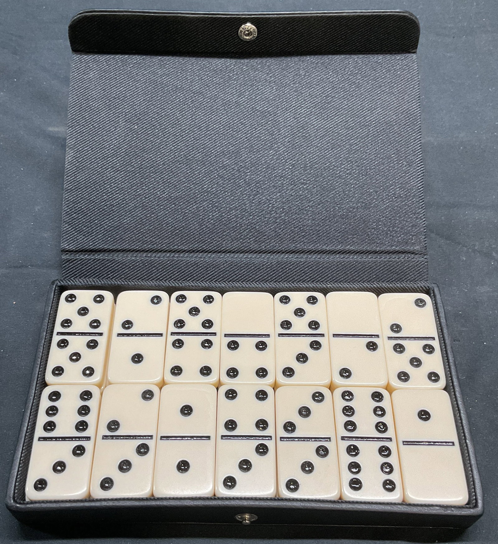 Danier Domino Set with Black Leather Case: Danier domino set with black leather case. Includes 28 domino pieces. Dominos measures approx. 2 x 1 inches. Case measures approx. 7 x 4.25 x 1 inches. Some wear to case consistent with exposure. Domi
