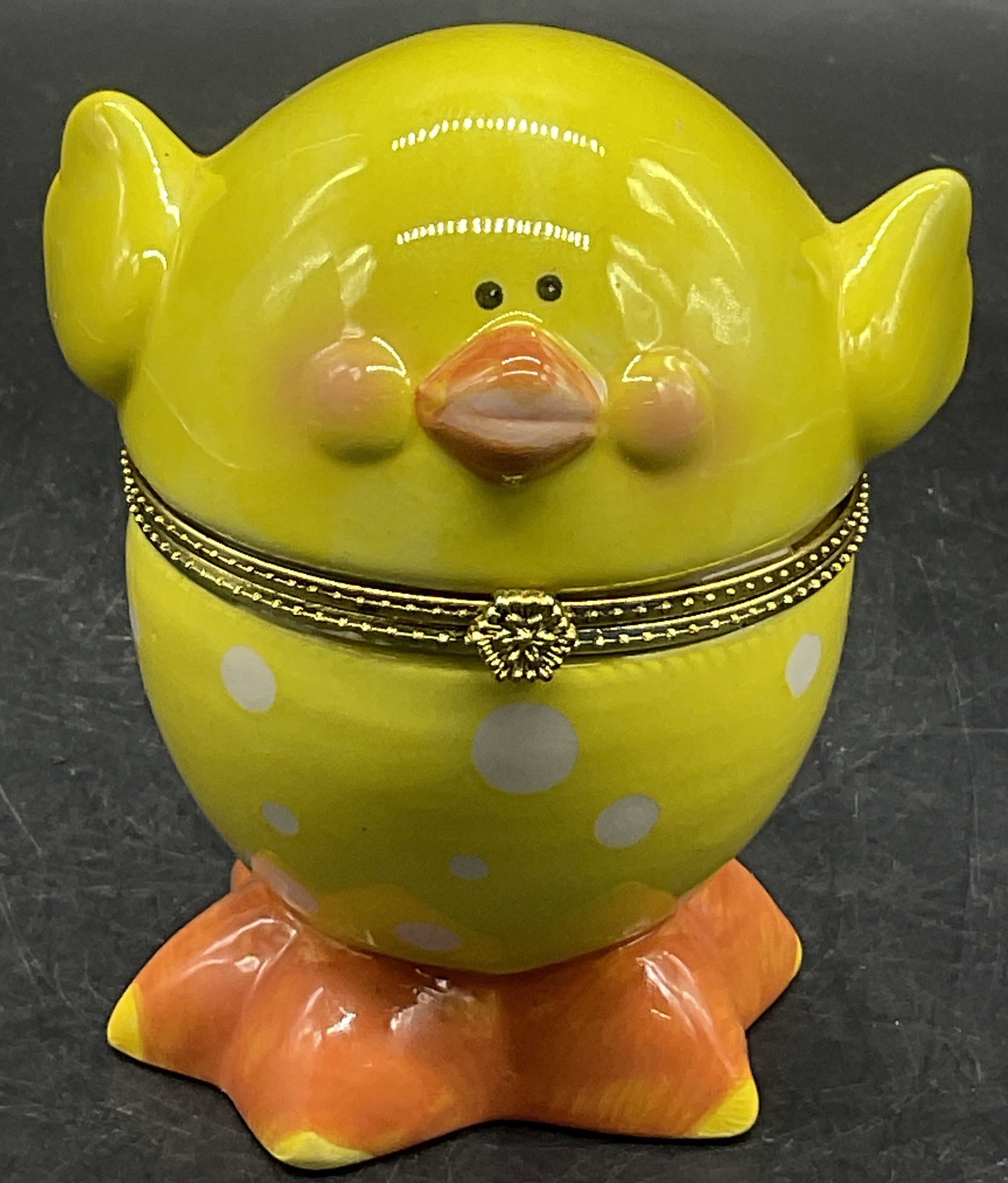 Yellow Ceramic Spotted Chick Figural Trinket Box: Yellow Ceramic Spotted Chick Figural Trinket Box. White, yellow, and orange hues. Opens with metal hinge hardware. Drilled hole to underside. Measures approx. 3.5H x 2.5W in. Wear to paint and pitting