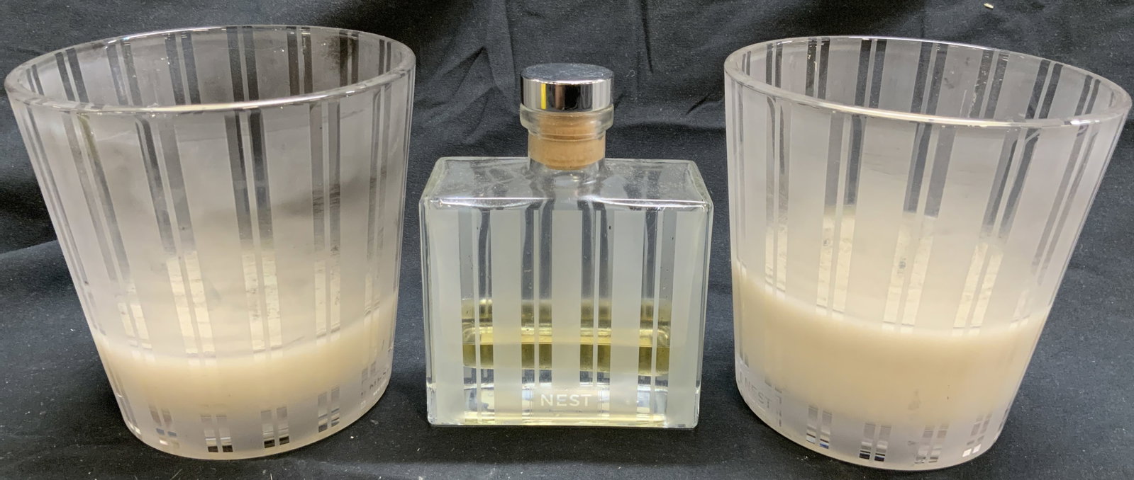 NEST Art Gls Candle Holders & Reed Diffuser Bottle: Diffuser bottle reads NEST NEW YORK. Lot includes 2 candles holders, & 1 Reed diffuser bottle. Each piece is glass with vertical frosted stripe detail. Reed diffuser bottle includes stopper. Candle ho
