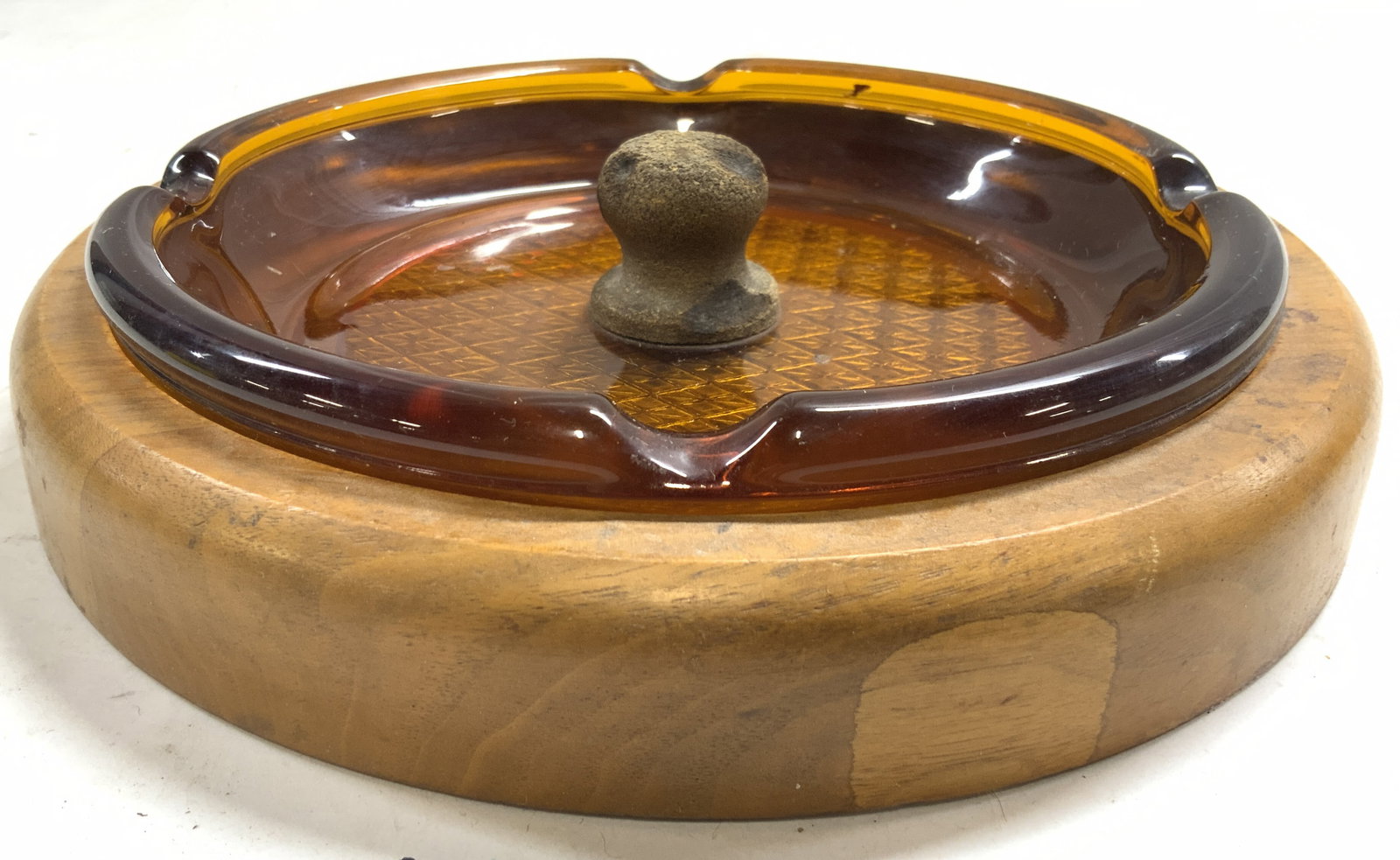 Vtg 1970s Walnut Wood Amber Gls Tapper Ashtray: Ashtray is vintage circa 1970s. Piece has tan toned walnut base and thick walled amber glass insert. Insert has cork handle in center underside of insert has geometric relief detail. Ashtray measures 