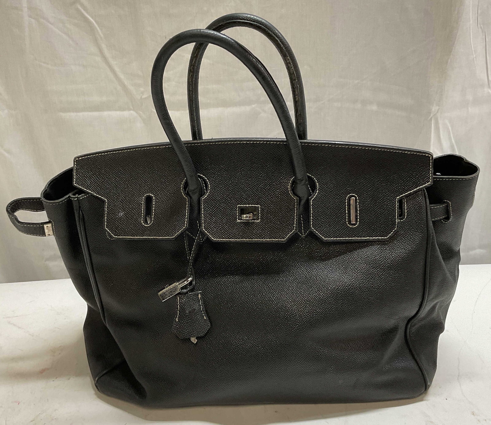 Vintage Black Leather Handbag: Vintage black leather handbag. White contrast stitching. Silver tone hardware. Measures approx. 12 x 7 x 10 inches. Wear to leather including, tearing, scratching, rubbing, peeling. The Benefit Shop d