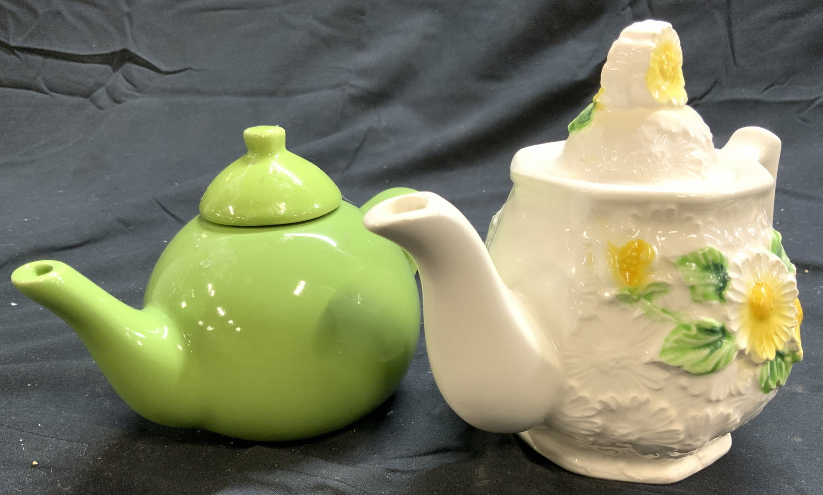 Lot2 Porcelain Teapots, Schylling & Rubens Orig LA: Lot includes 1 green toned teapot (SCHYLLING) & 1 white toned teapot with green and yellow toned floral and leaf detail (RUBENS ORIGINAL LA). Each piece includes lids. Largest teapot measures approxim