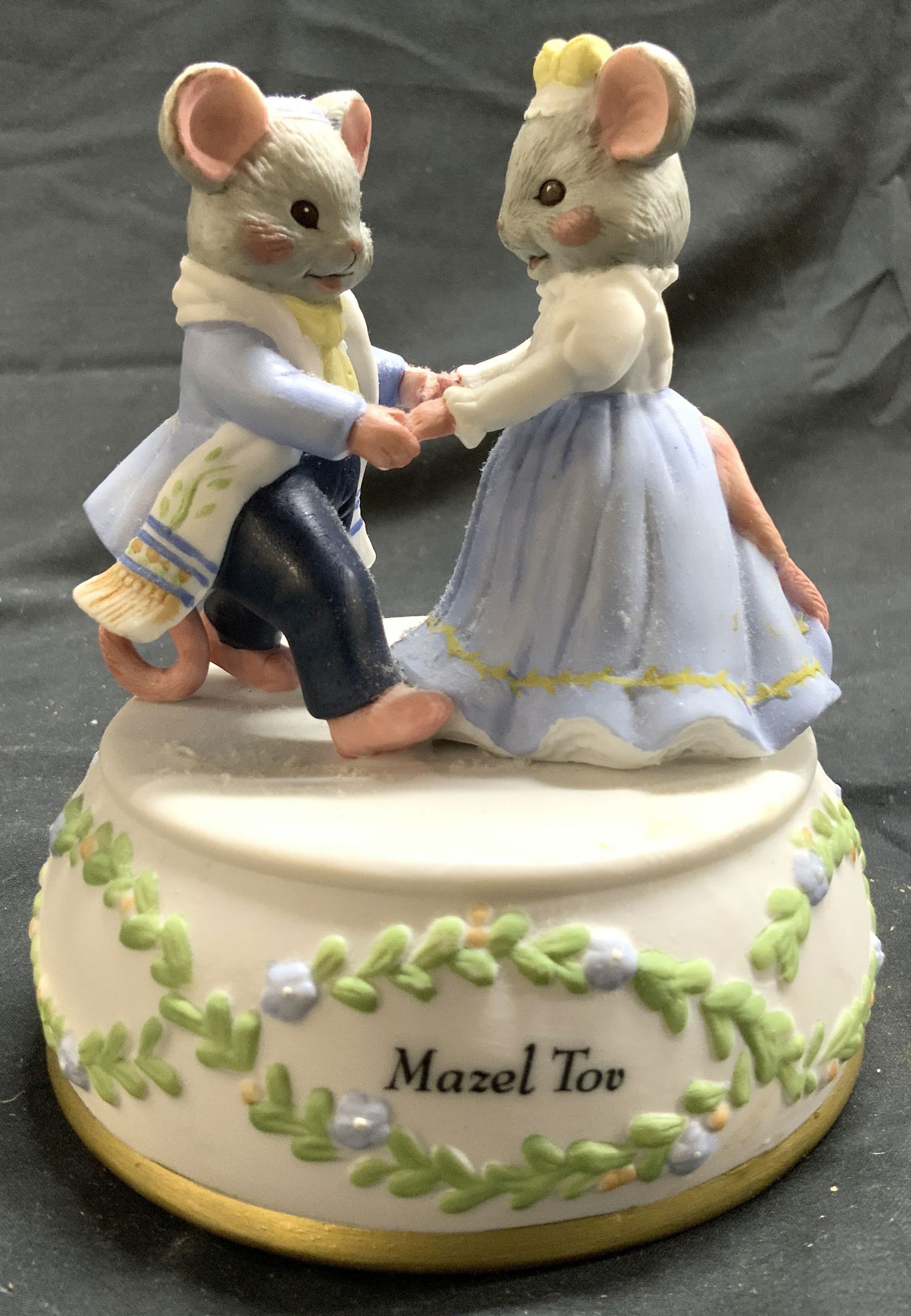 MOUSE-L-TOV Porcelain Mouse Music Box: Underside reads MOUSE-L-TOV. Music box is porcelain. Piece depicts a mouse couple dancing. Base has multi toned floral and leaf detail. Underside has music box wind with letter S. Music box appears to