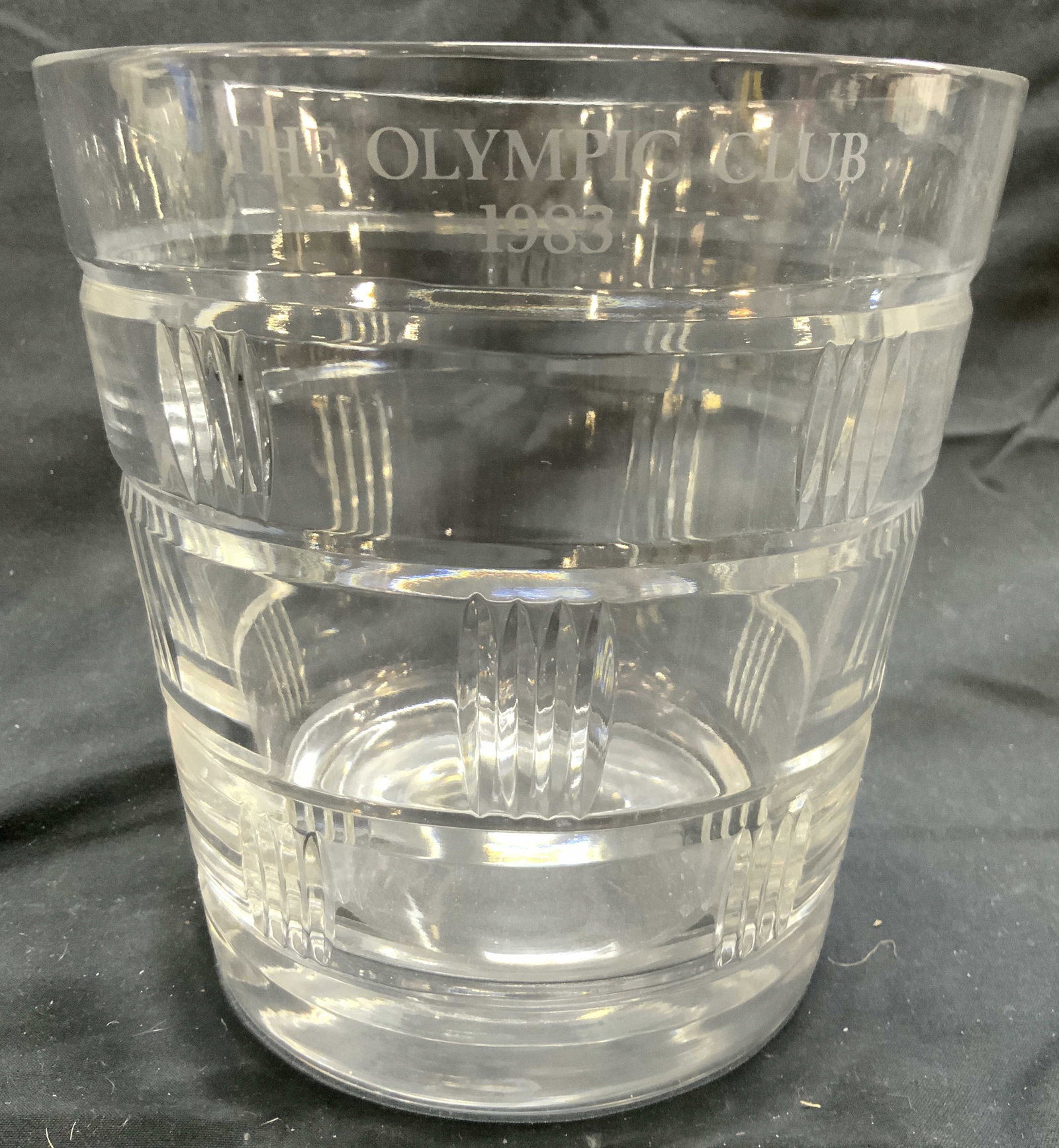 Monogrammed Crystal Ice Bucket Vessel: Ice Bucket is monogrammed THE OLYMPIC CLUB 1983. Piece is crystal. Vessel has horizontal stripe relief detail. Ice bucket measures approximately 6 inches tall and wide. Ice bucket, crystal ice bucket,