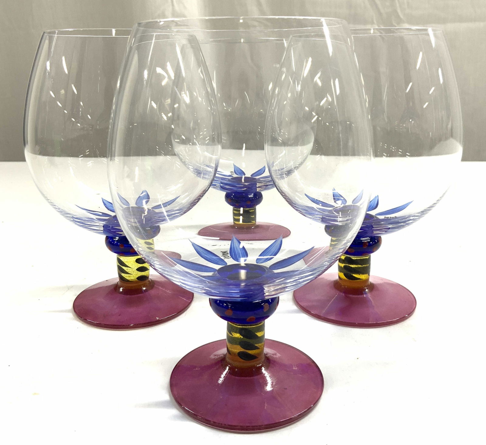 KOSTA BODA KEN DONE Set 4 Art Gls Brandy Glasses: Undersides are signed KOSTA BODA KEN DONE COLL. Lot includes 4 brandy glasses. Each are painted with multi toned floral detail bases are each pink toned. Vessels each measure approximately 6 inches ta