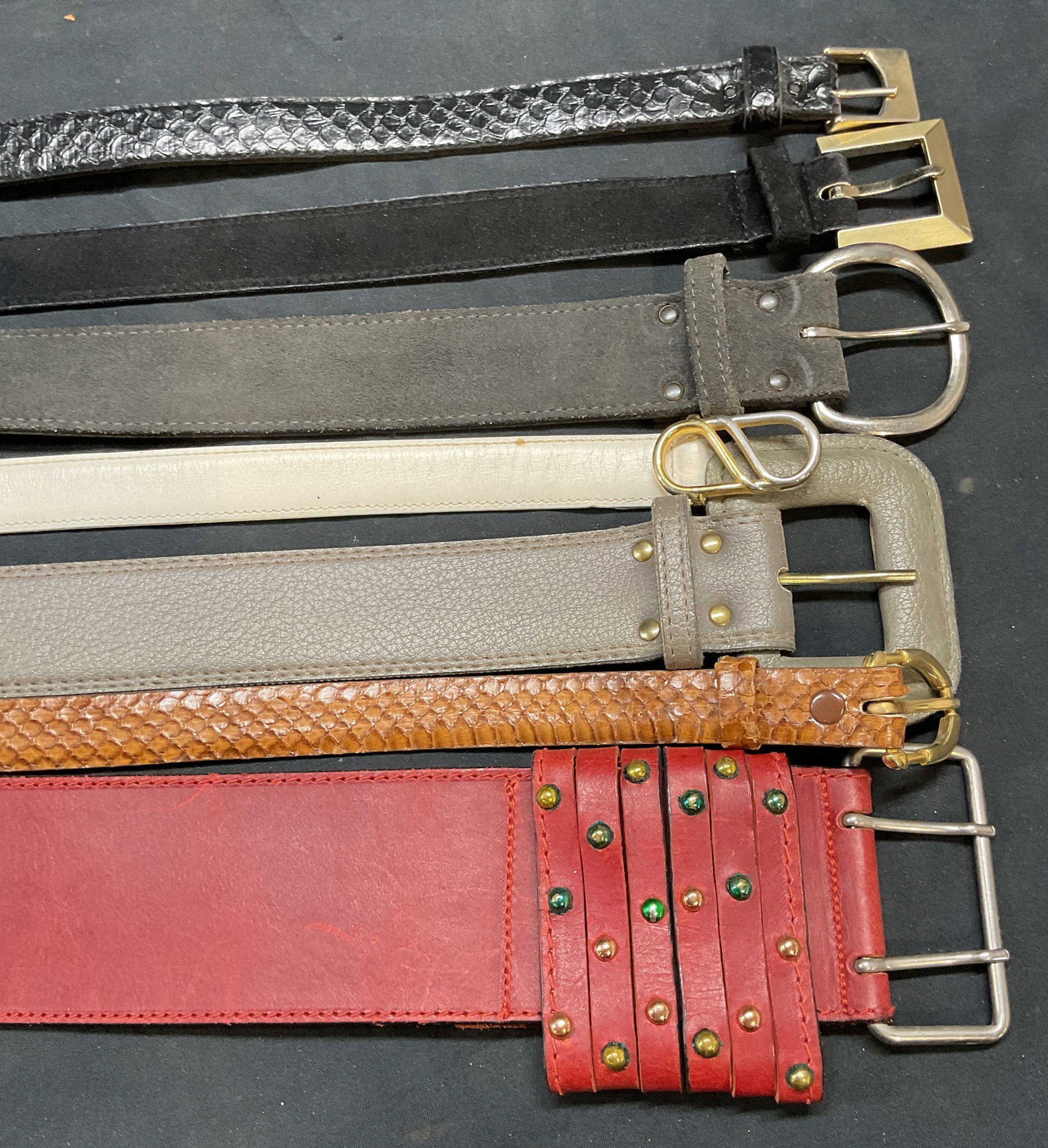 Group Fob Trading + Leather & Snakeskin Belts: Group lot of leather and snakeskin belts. One black leather belt signed Fob Trading, size medium. Group of leather and snakeskin belts in black, red, brown, gray, and white. Longest belt approx. 39.5 