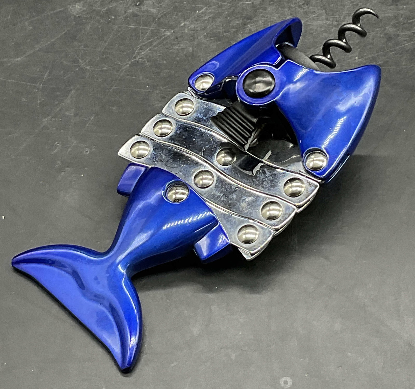 Fish Form Accordion Corkscrew Bottle Opener: Fish Form Accordion Corkscrew Bottle Opener. Blue and silver toned metal. Measures approx. 6.5L x 3W in. Surface wear consistent with age, use, and exposure. home decor, home accents, homewares, house