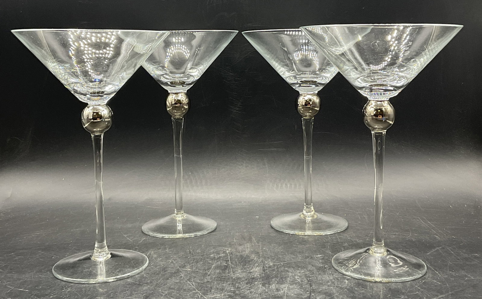 Set 4 Art Glass Martini Stemware: Set 4 Art Glass Martini Stemware. Clear glass with spherical metallic glass accent beneath the top. Measures approx. 7.75H x 5W in. Slight variations to sizes. Surface wear consistent with age, use, a