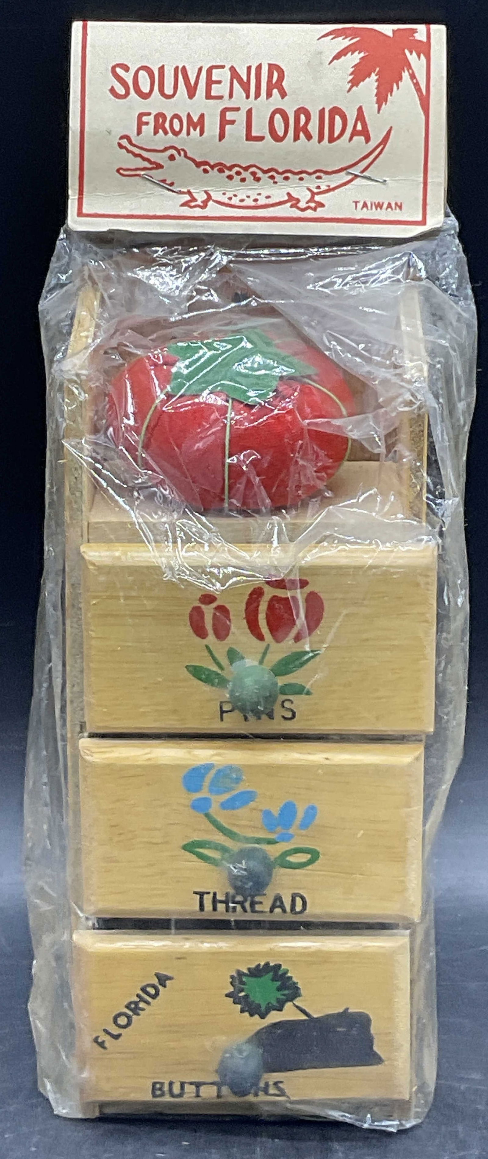 SOUVENIR FROM FLORIDA NIP Wooden Sewing Storage: SOUVENIR FROM FLORIDA New in Package Wooden Sewing Storage. Not inspected out of packaging. Wooden three drawer sewing storage. Comes with a red fabric tomato pin cushion. Some drawers appear to be lo