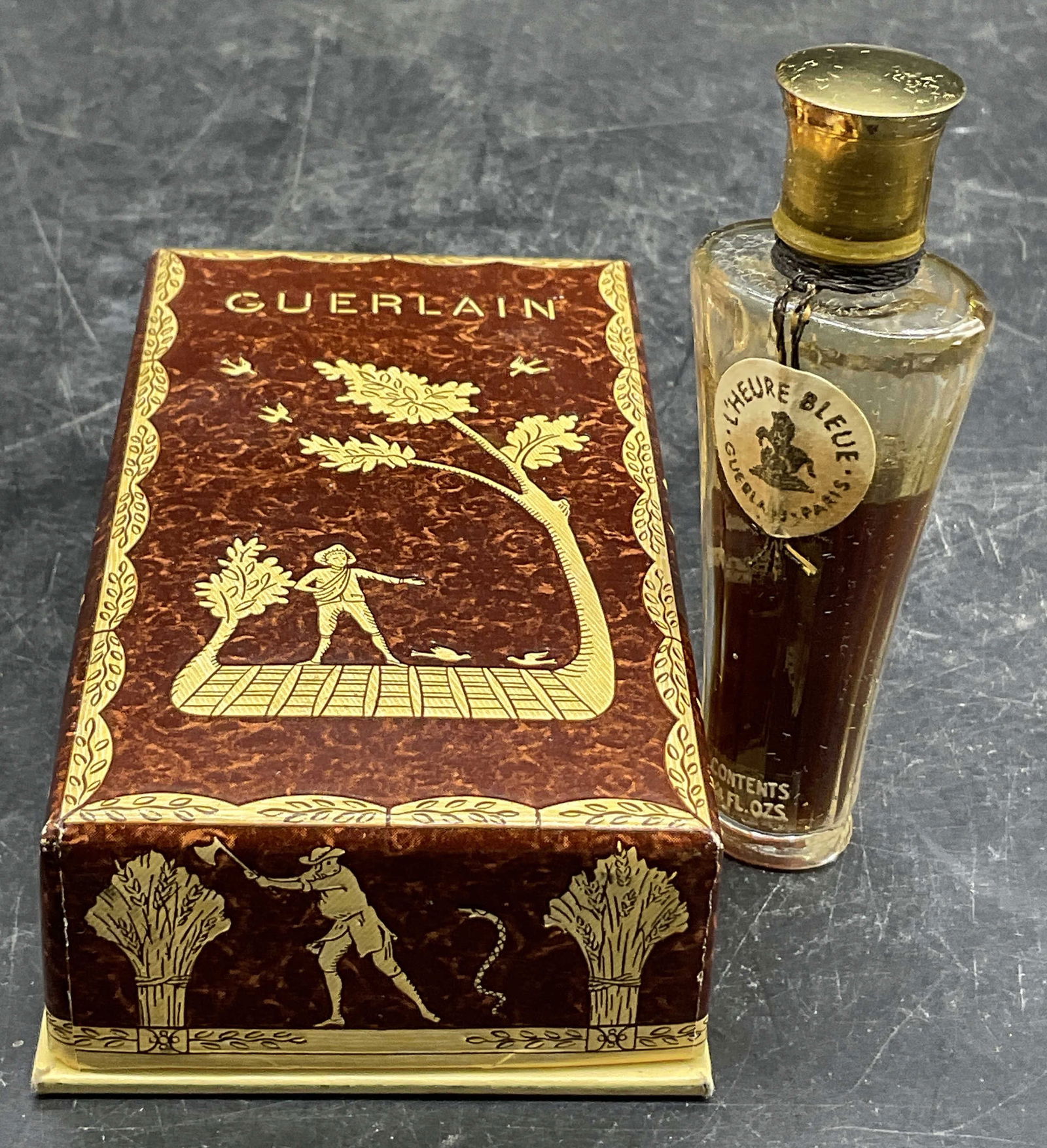 GUERLAIN Perfume Box W/ LHEURE BLEUE Bottle, Paris: GUERLAIN Paris Perfume Box W/ LHEURE BLEUE Bottle. Box crafted from cardboard and wrapped with a paper design. Obverse reads GUERLAIN. Box opens to reveal glass perfume bottle with some liquid to the
