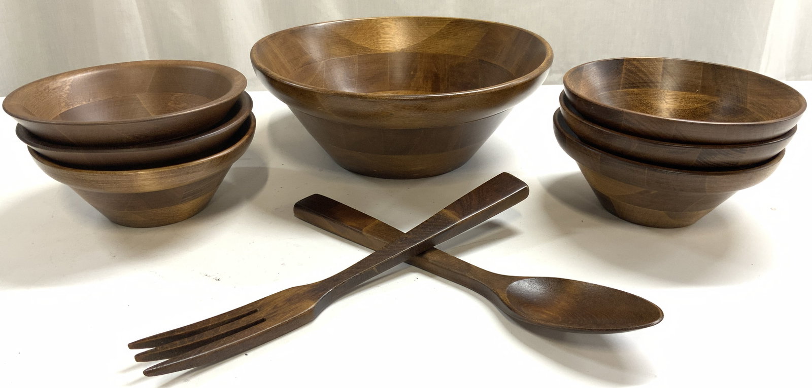 Set 9 Teakwood Salad Serving Set: Lot includes 1 serving bowl, 6 bowls, 1 salad serving fork, and 1 salad serving spoon. Each piece is brown toned. Appears to be teakwood. Serving bowl measures approximately 9.5 inches wide 3.5 inches