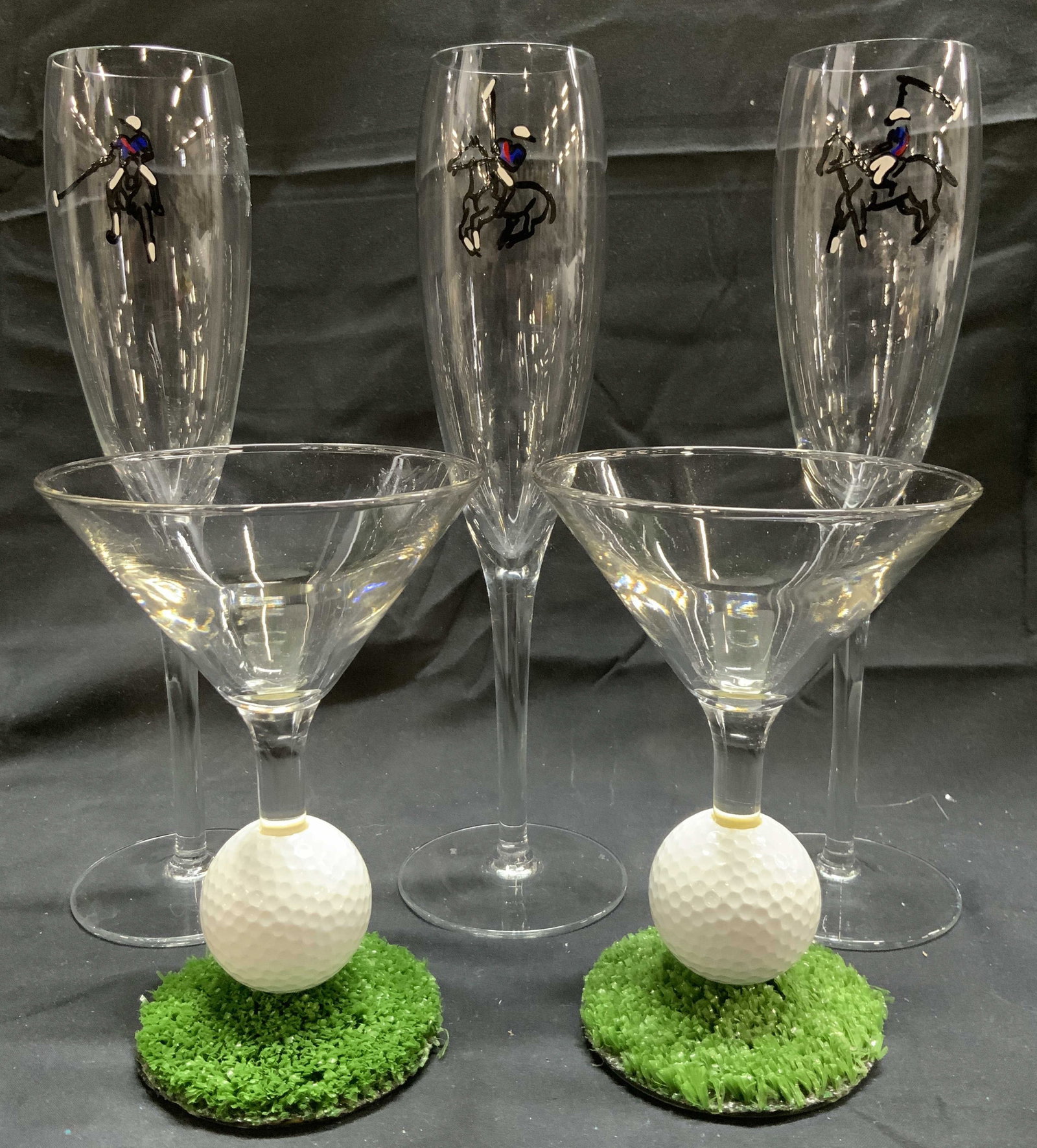 Lot 5 Polo Champagne Flutes & Golf Martini Glasses: Lot includes 3 champagne flutes with painted polo player detail, & 2 martini glasses with golf ball and turf stems. Each piece is glass. Champagne flutes measure approximately 10 inches tall 2.5 inche