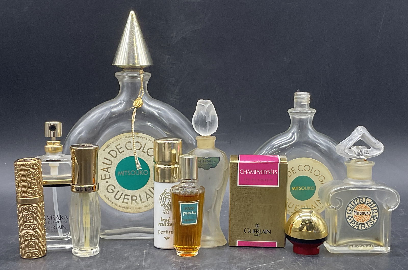 Grp Lot Vintage Glass Perfume Bottles, GUERLAIN +: Group Lot Vintage Glass, Metal, and Plastic Perfume Bottles. Lot includes GUERLAIN bottles and others. Largest measures approx. 7.5H x 5W in. Lot includes some loose fragrance bottle caps. Some bottle