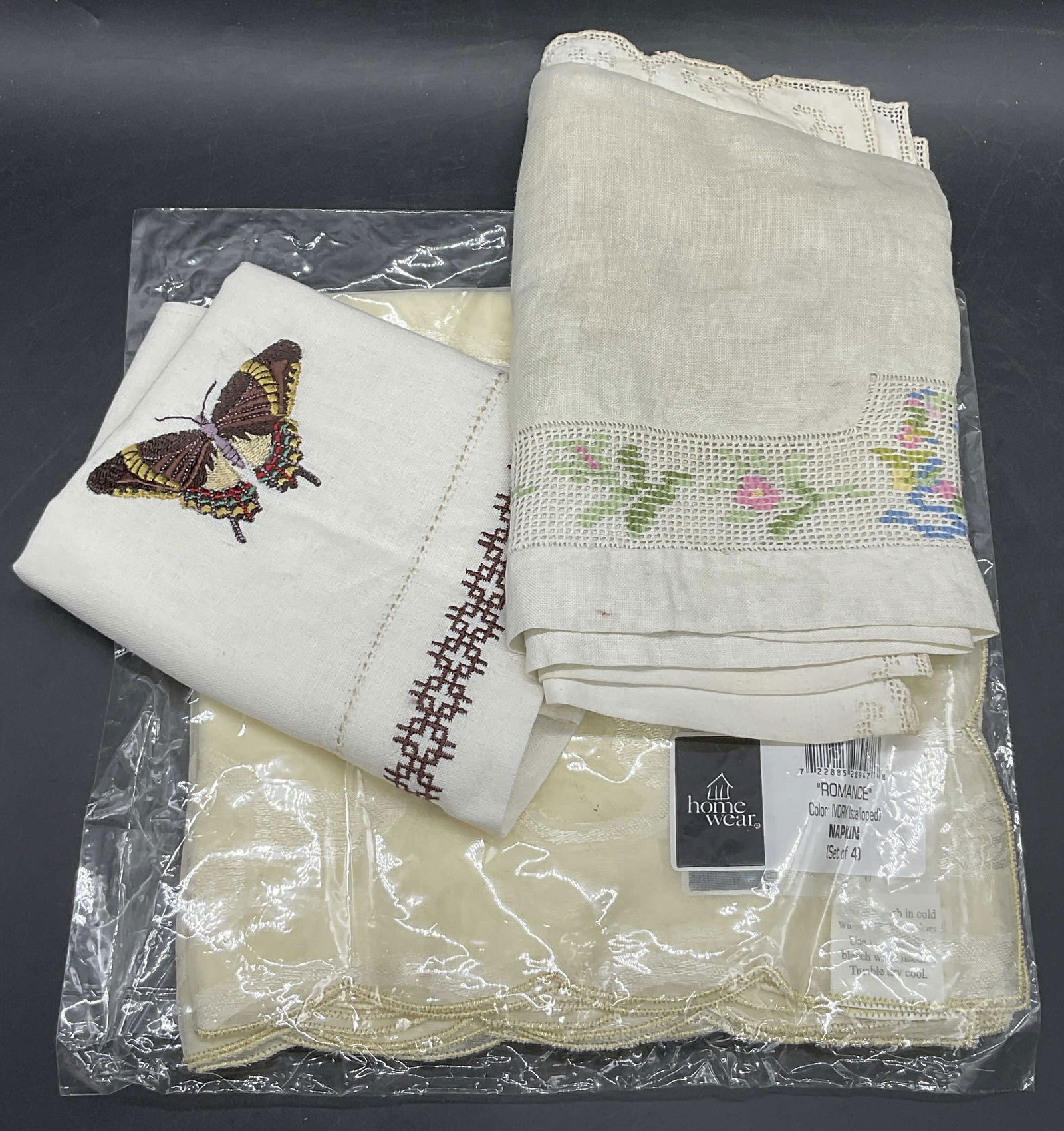 3 Table Linens / Tea Towels, NIP HOMEWEAR Napkins+: Two vintage table linens / tea towels and one new in package HOMEWEAR set of four fabric napkins. The vintage linens feature an embroidered butterfly motif or a multicolored embroidered floral motif.