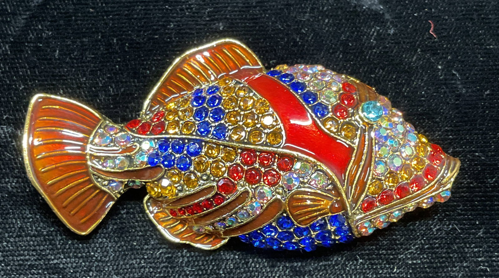 Gold Tone Crystal & Enamel Fish Brooch: Gold tone multicolor crystal and enamel decorated fish motif brooch. Hinge pin on underside. Measures approx. 2.75 x 1.25 inches. Some wear including scratching observed. Jewelry, estate jewelry, cost