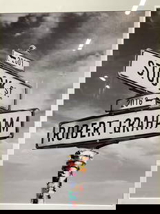 Framed Black & White Road Sign Lithograph: Framed lithograph. Black and white road sign reads 2001 Stock St and 2016 Robert Graham with color detail on pole. Framed in black wood frame under mat. Not examined out of frame. Measures approx 24 x