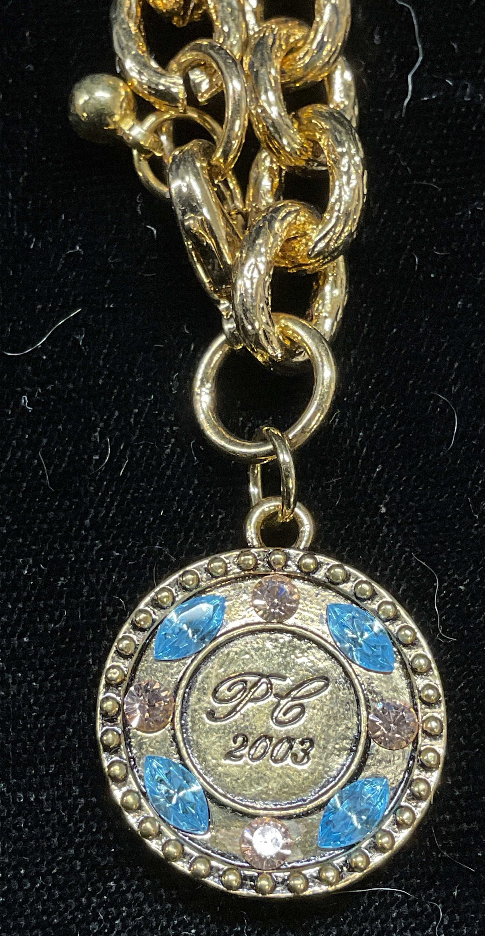 Avon Gold Tone Chain Crystal Pendant Bracelet: 2003 Avon gold tone chain bracelet with gold tone pendant and crystal decoration. Pendant reads PL 2003. Signed on pendant. Bracelet measures approx 7 inches long. Some wear including scratching obser