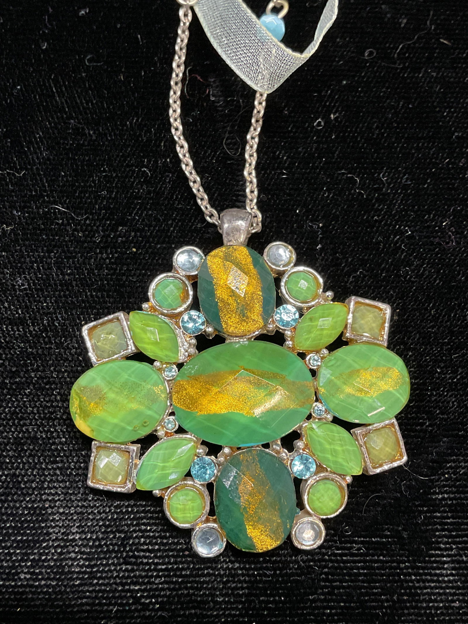 Vintage Silver Tone Green Crystal Pendant Necklace: Vintage silver tone pendant necklace with ribbon and green crystal decoration. Drop length approx 9.5 inches. Pendant measures approx 1.5 inches wide. Some wear including scratching observed. Jewelry,