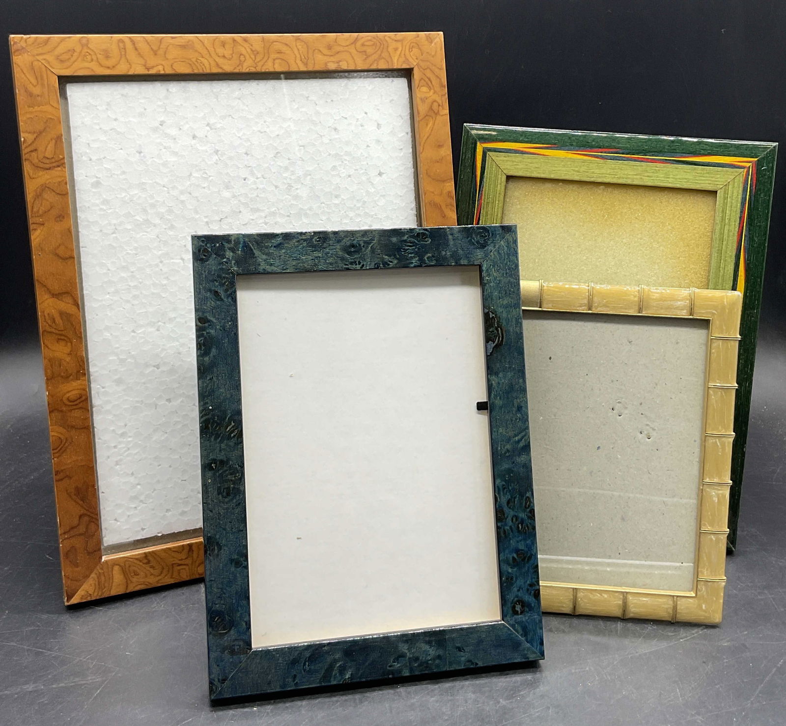 Lot 4 Wood & Metal Picture Frames, ASHLEIGH MANOR+: Four wood or metal picture frames with kickback stands. Rectangular forms. One sticker to reverse reads ASHLEIGH MANOR. Largest measures approx. 11H x 9.25W in. Some losses to backings. Surface wear c