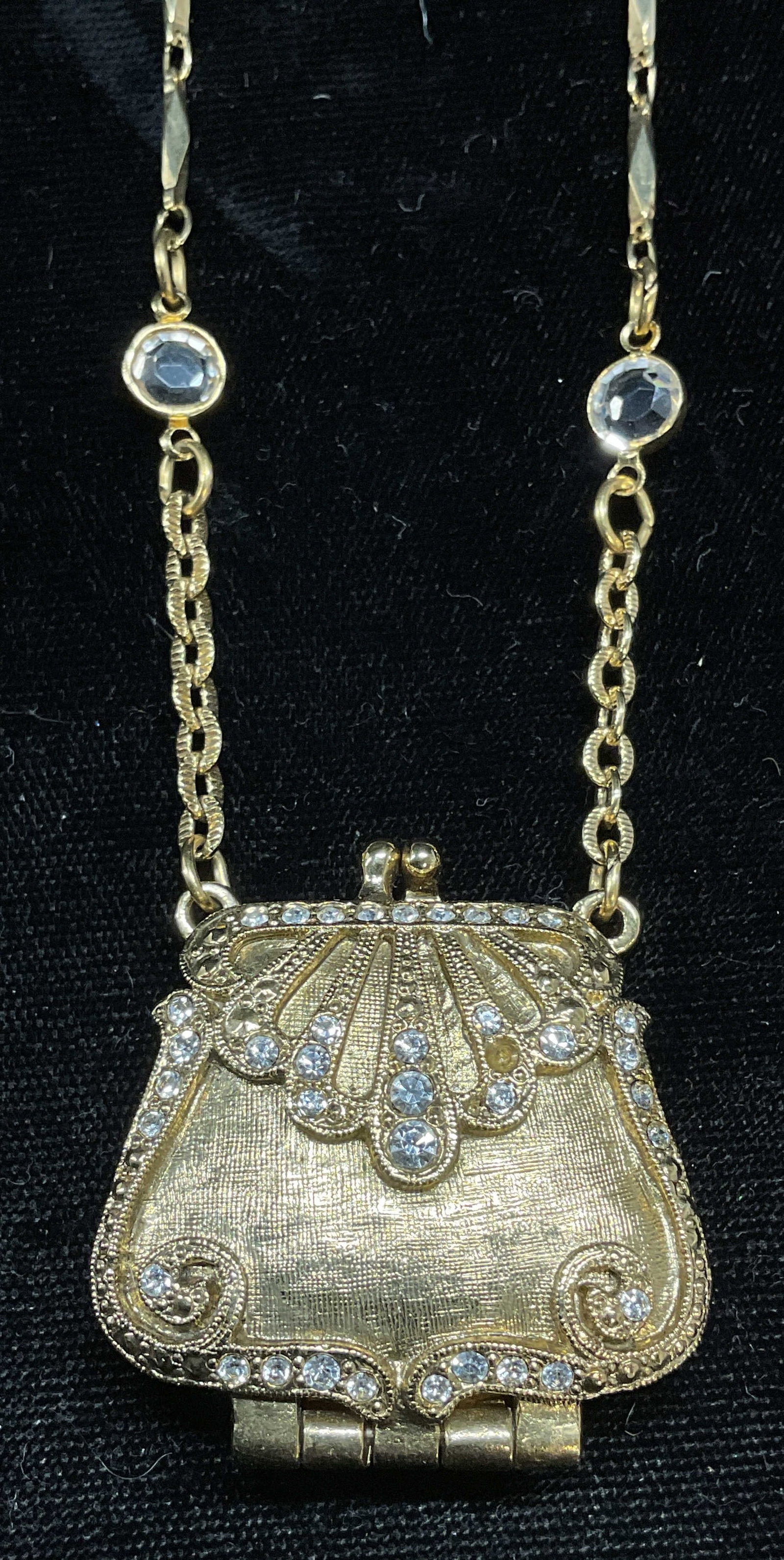 1920 Label Gold Tn Purse Pendant Locket Necklace: Vintage 1920 (brand label) gold tone pendant necklace. Purse motif locket pendant. Crystal decoration. Signed on hang tag. Drop length approx 13 inches. Pendant approx 1 x 1.5 inches. Some wear includ