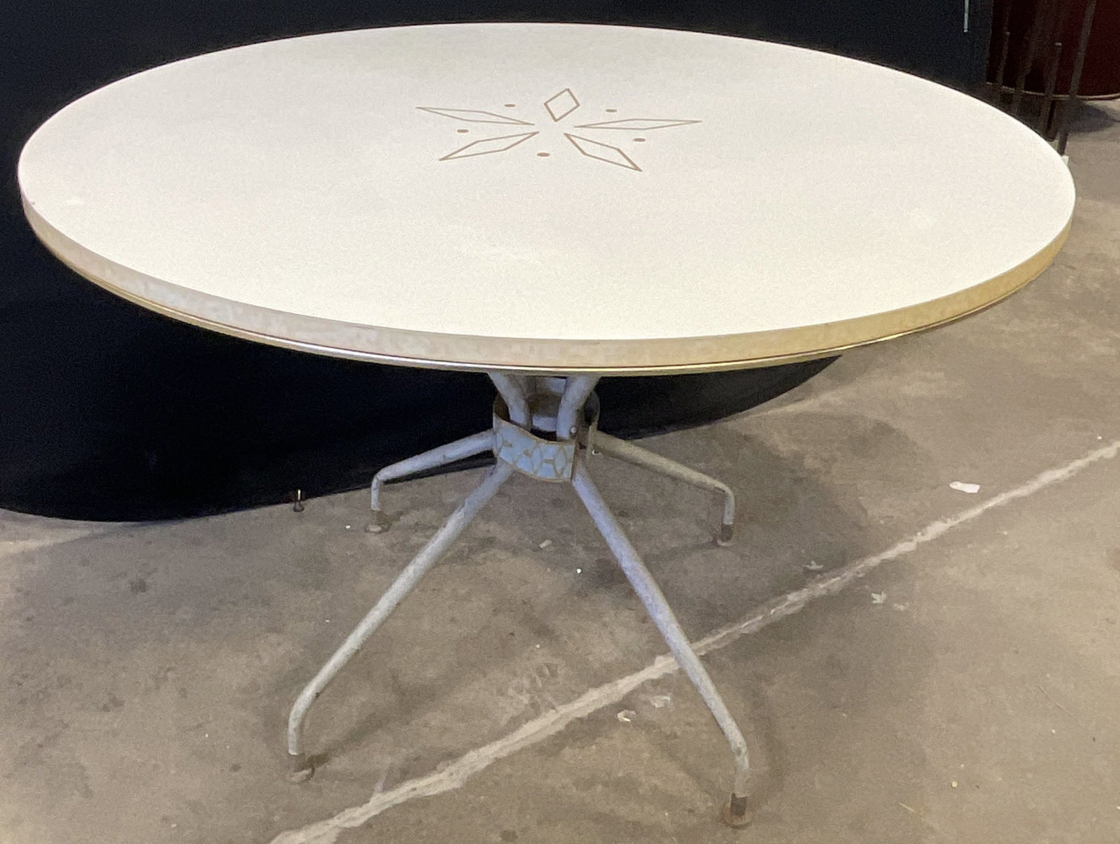 Vintage Mid Century Starburst Motif Round Table: Vintage Mid Century Starburst Motif Round Table. White round top. The top appears to be crafted from veneer. The base of the table has a decorative blue and gold tone patterned band around the central