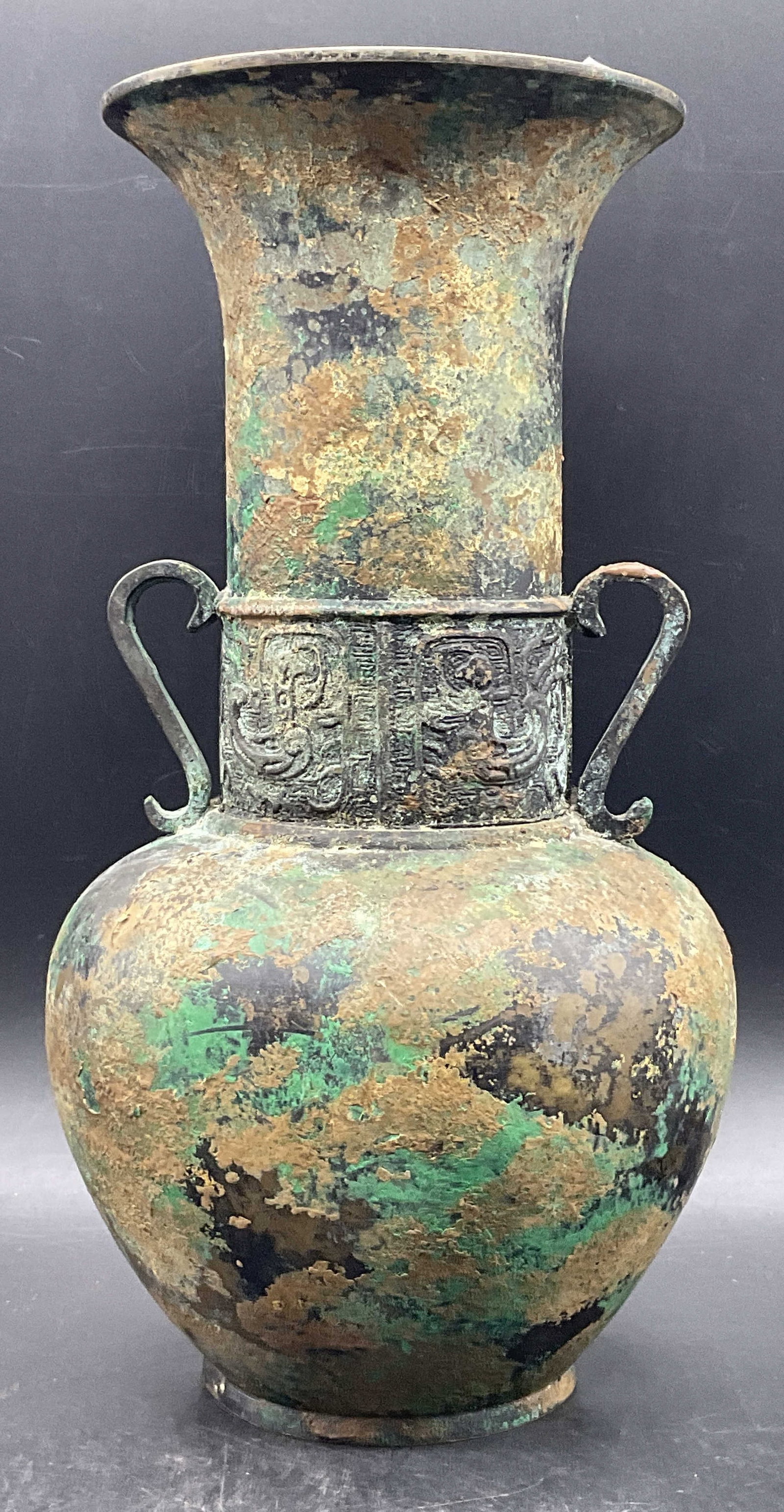 Vintage Metal Twin Handled Vase: Vintage Metal Twin Handled Vase. Bronze and patina style finish to the metal. Raised design to the center. Measures approx. 12.25H x 6W in. Weighty piece. Surface wear, discoloration, and wear to meta