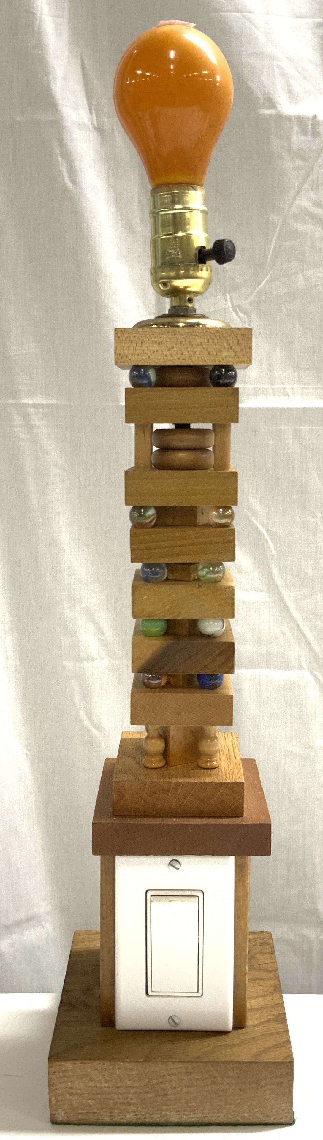 Wood & Marble Bead Table Lamp W Switch: Lamp is crafted from wood and marbles. Piece has white toned light switch to base. Lamp has square form base. Piece appears to be hand crafted. Lamp measures approximately 24 inches tall 5.5 inches wi