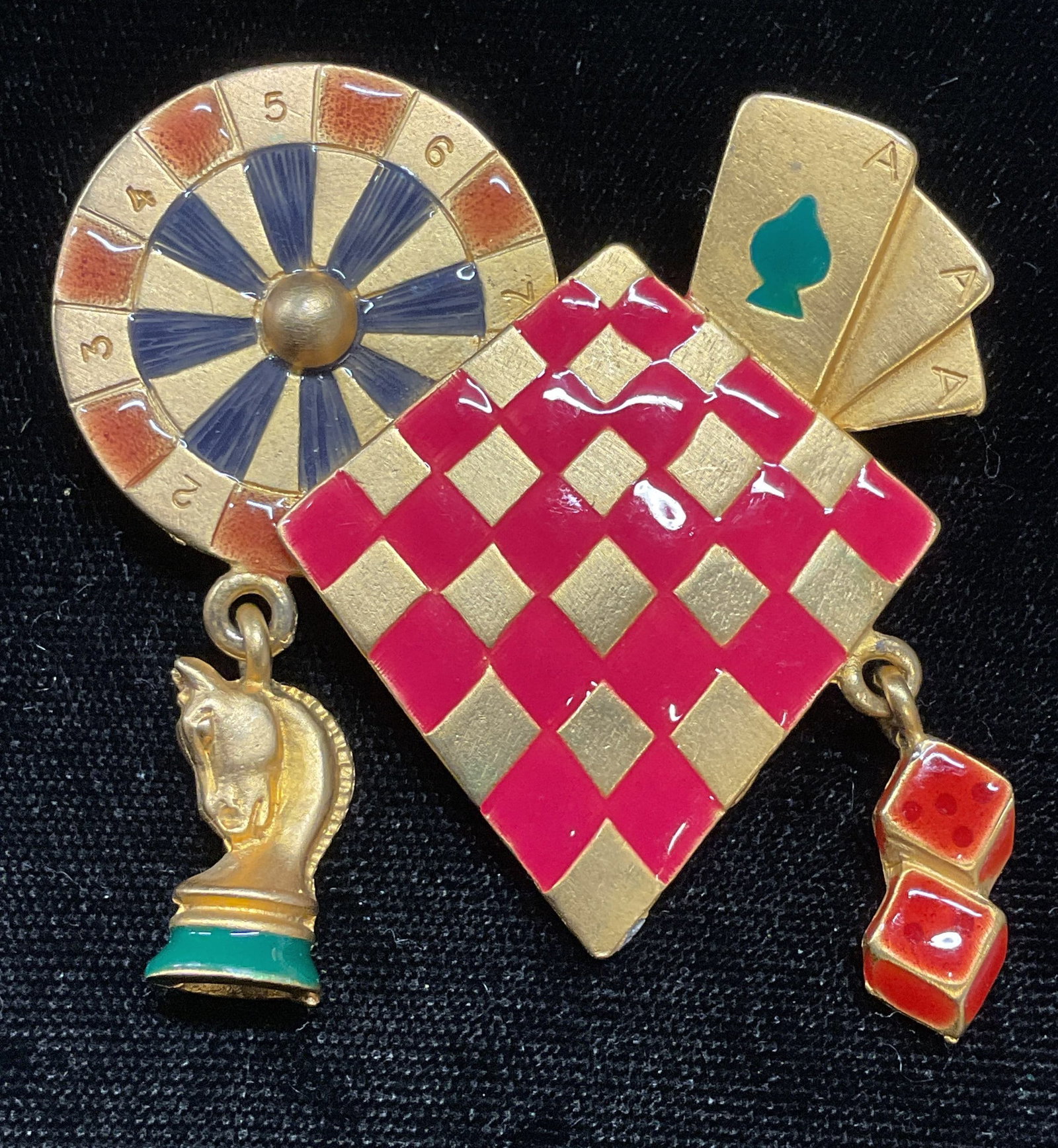 Vtg Gold Tn Enamel Casino Games Brooch: Vintage gold tone brooch with enamel decoration. Casino, gambling, gaming motifs. Hinge pin on underside. Some wear including scratching. Loss to one charm. Approx 2 in by 2 in. Jewelry, estate jewelr