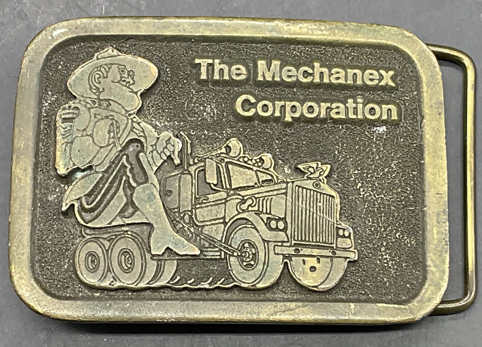 1976 THE MECHANEX CORPORATION Metal Belt Buckle: Vintage belt buckle from 1976 featuring The Mechanex Corporation logo. Reverse reads COPYRIGHT 1976, THE MECHANEX MOUNTIES WANT YOU, PROPERTY OF. Brand trademark / other verbiage to reverse is illegib