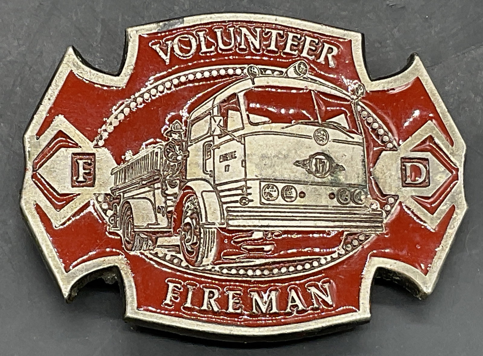 1979 INSTYLE Red Enamel Metal Firefighter Buckle: 1979 INSTYLE Red Enamel Metal Firefighter Belt Buckle. Obverse reads VOLUNTEER FIREMAN. Reverse reads 1979 INSTYLE. Measures approx. 2.5L x 3.25W in. Surface wear and discoloration present. Wearables,