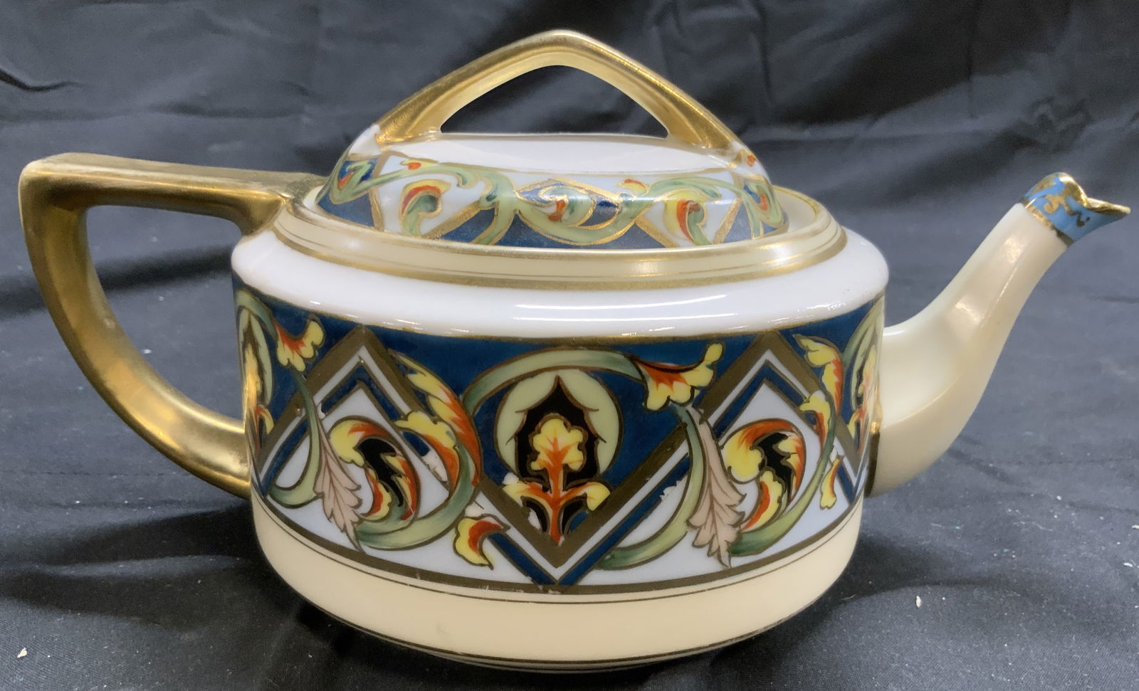 NIPPON Hand Painted Porcelain Teapot W Lid: Underside is marked NIPPON HAND PAINTED. Teapot is white toned and porcelain with multi toned floral and geometric detail. Teapot includes lid. Piece has areas of gilt detail. Teapot measures approxim