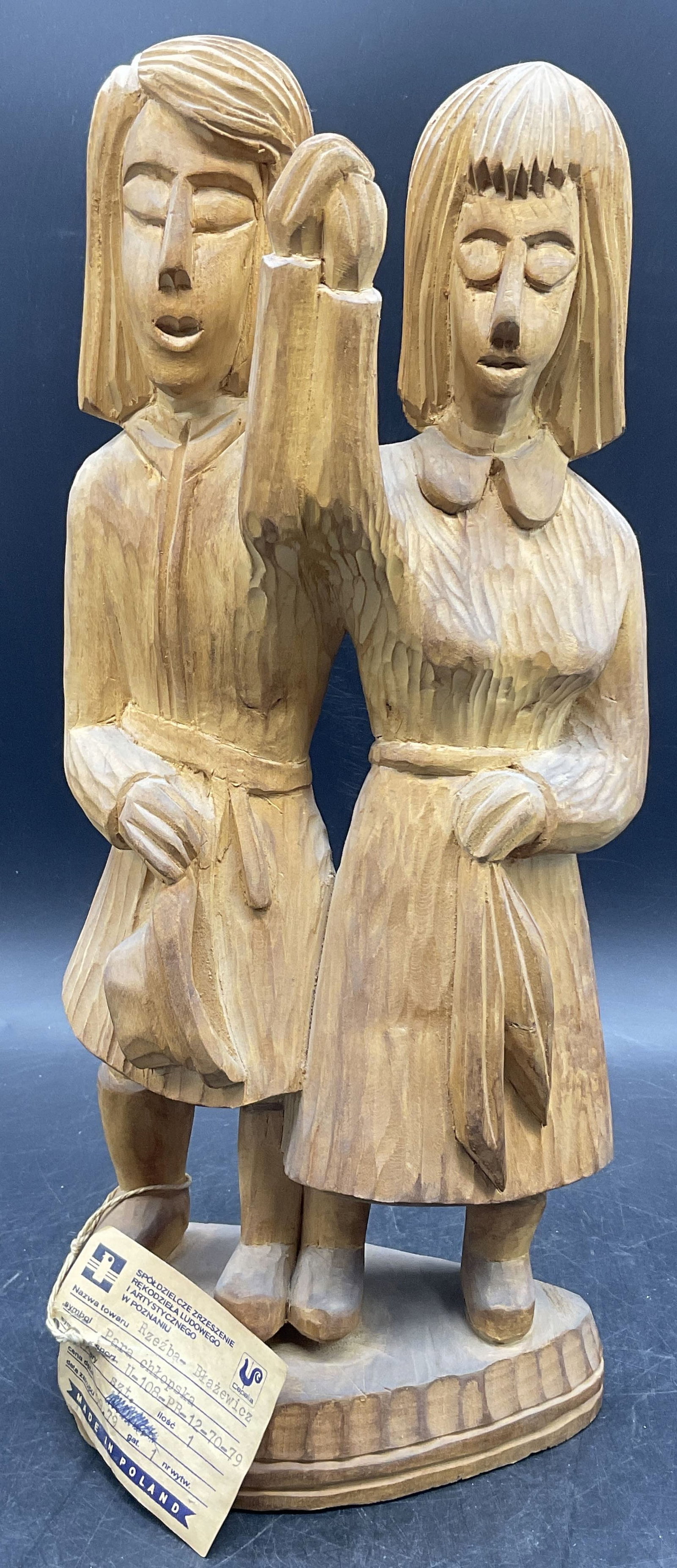 JB Hand Carved Polish Wooden Statue W/ Org Tag 14i: Hand Carved Polish Wooden Statue. Depicts two people holding hands. Original tag attached, primarily in Polish, can read MADE IN POLAND. Underside of figure signed JB. Measures approx. 14H x 5.75W in.