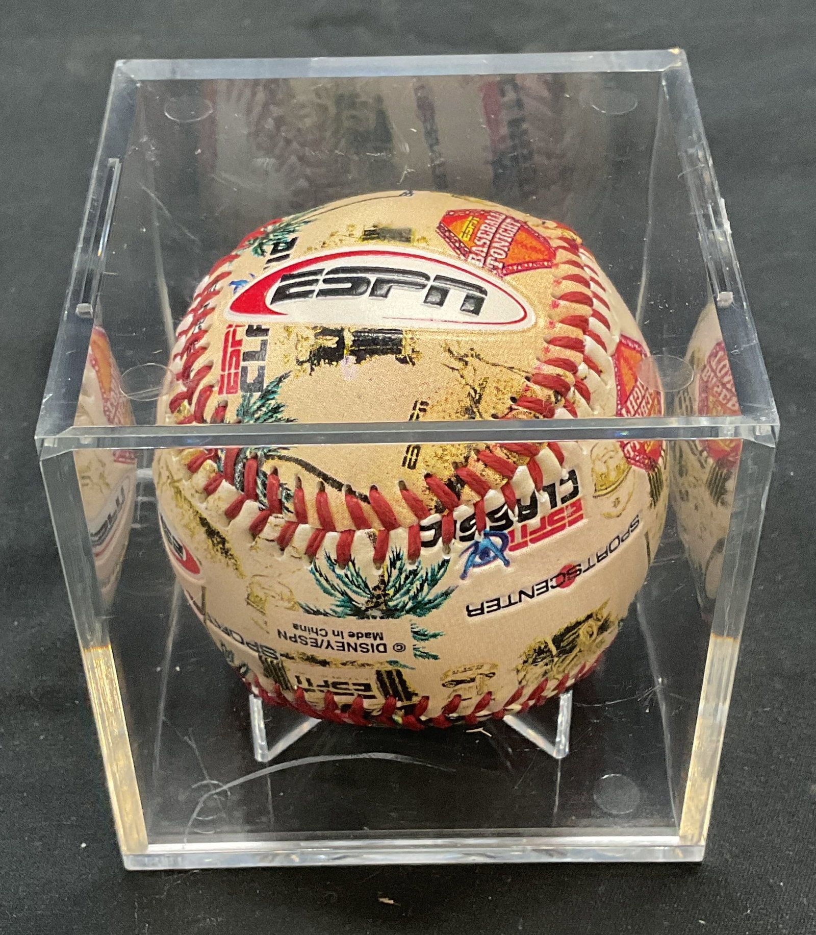ESPN/Disney Logo Souvenir Baseball: ESPN souvenir baseball with logo design. Marked ESPN/Disney. Includes acrylic case. Baseball measures approx. 2.75 inches wide. Some surface wear consistent with exposure. Property of Fifth Avenue, Ma