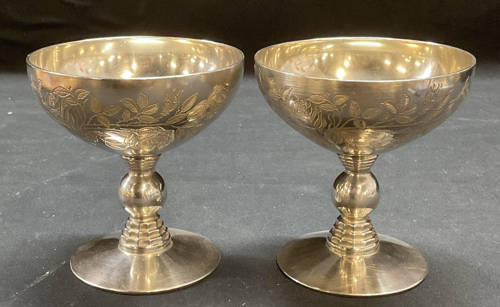 Pair Rockwell Sterling over Glass Coupe Glasses: Pair of vintage Rockwell sterling silver over glass coupe glasses. Embossed floral pattern on bowls. Signed on undersides. Marked sterling. Measure approx 3.75 x 4 inches. Some wear including scratchi