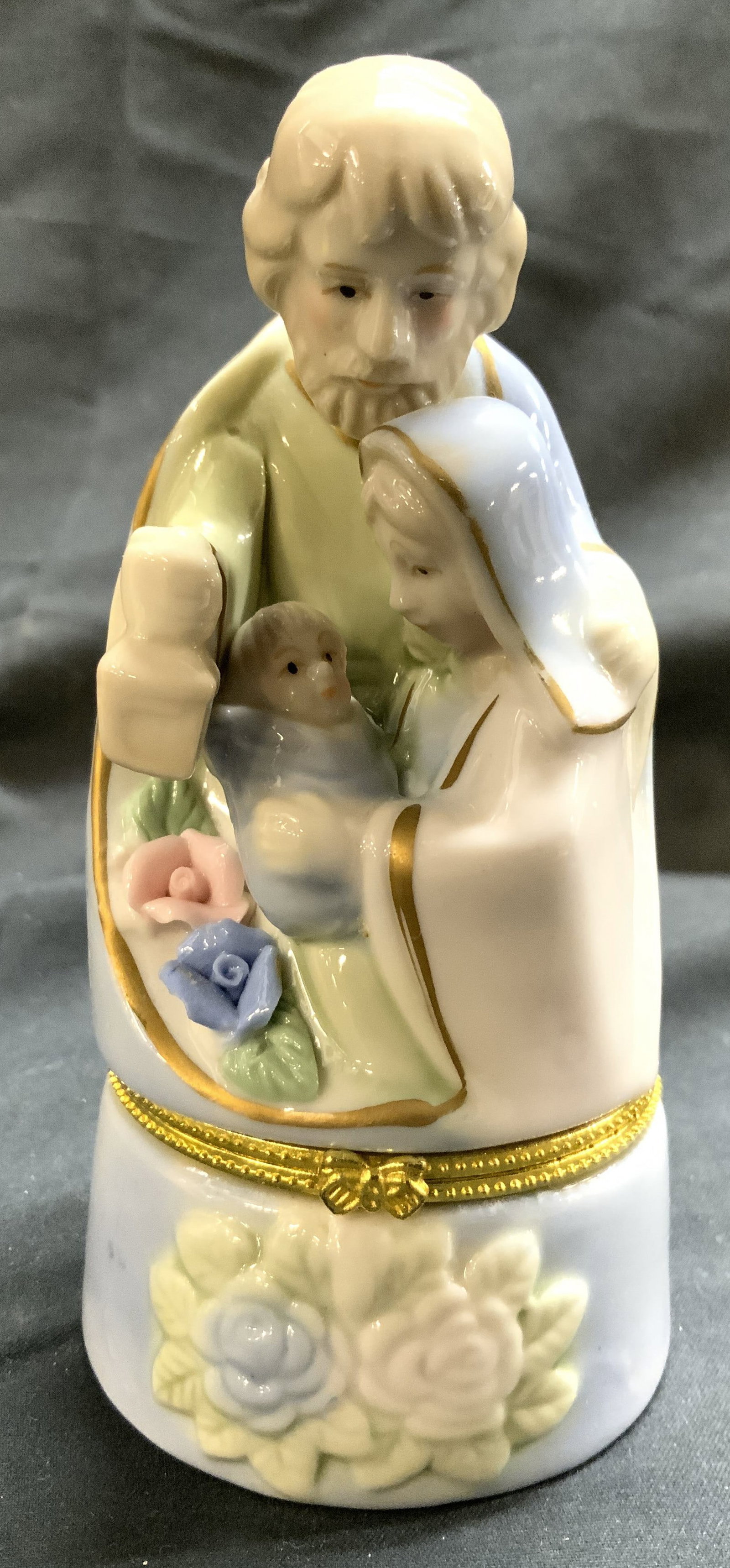 Porcelain Nativity Scene Trinket Box W Lid: Trinket box is porcelain. Piece is possibly vintage. Trinket box has hinged lid. Piece depicts a nativity scene. Floral and leaf detailed areas in addition to gilt detail. Trinket box measures approxi
