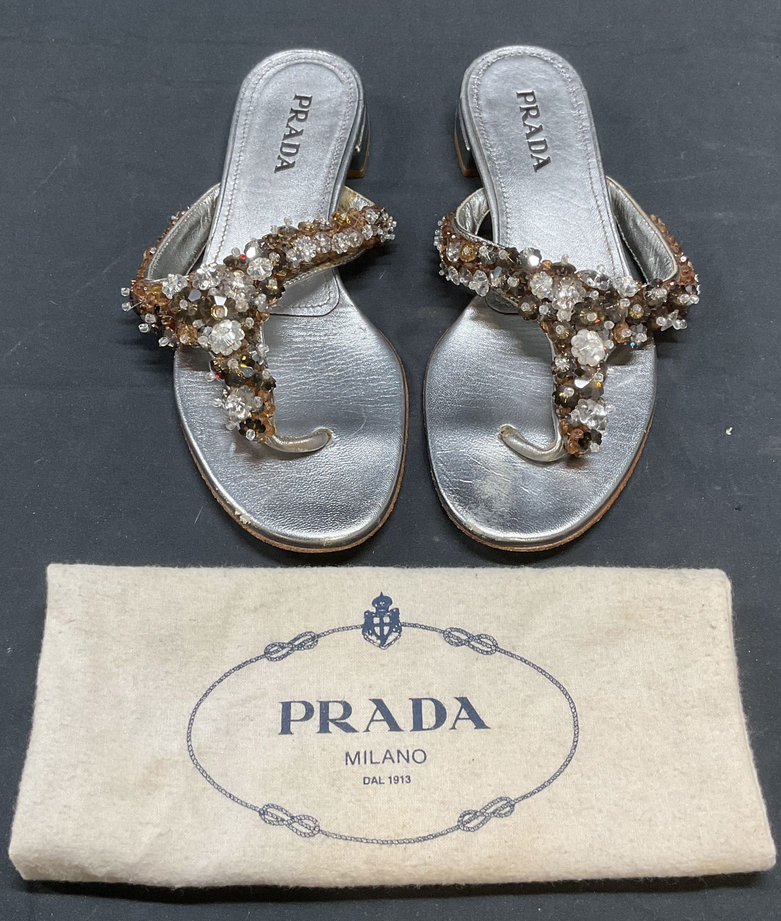 Prada Silver leather Beaded Sandals, Italy: Prada silver tone leather sandals with colorless and brown beaded floral decoration. Size 36. Made in Italy. Includes dust bag. Surface wear consistent with exposure, some loss to beading, see photogr