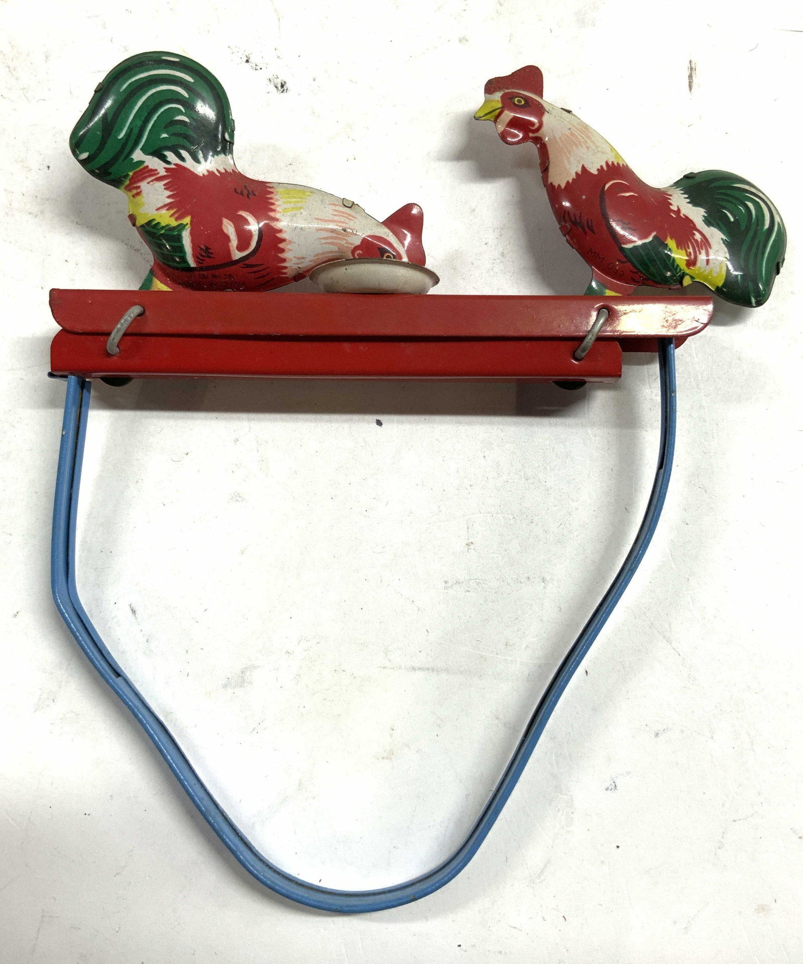 Vintage Pecking Rooster Tin Toy: Piece is vintage. Slider underneath moves to make rooster figures peck at bowl. Piece is red, white blue and green toned. Piece measures approximately 6 inches tall 5.75 inches wide. Pecking rooster t