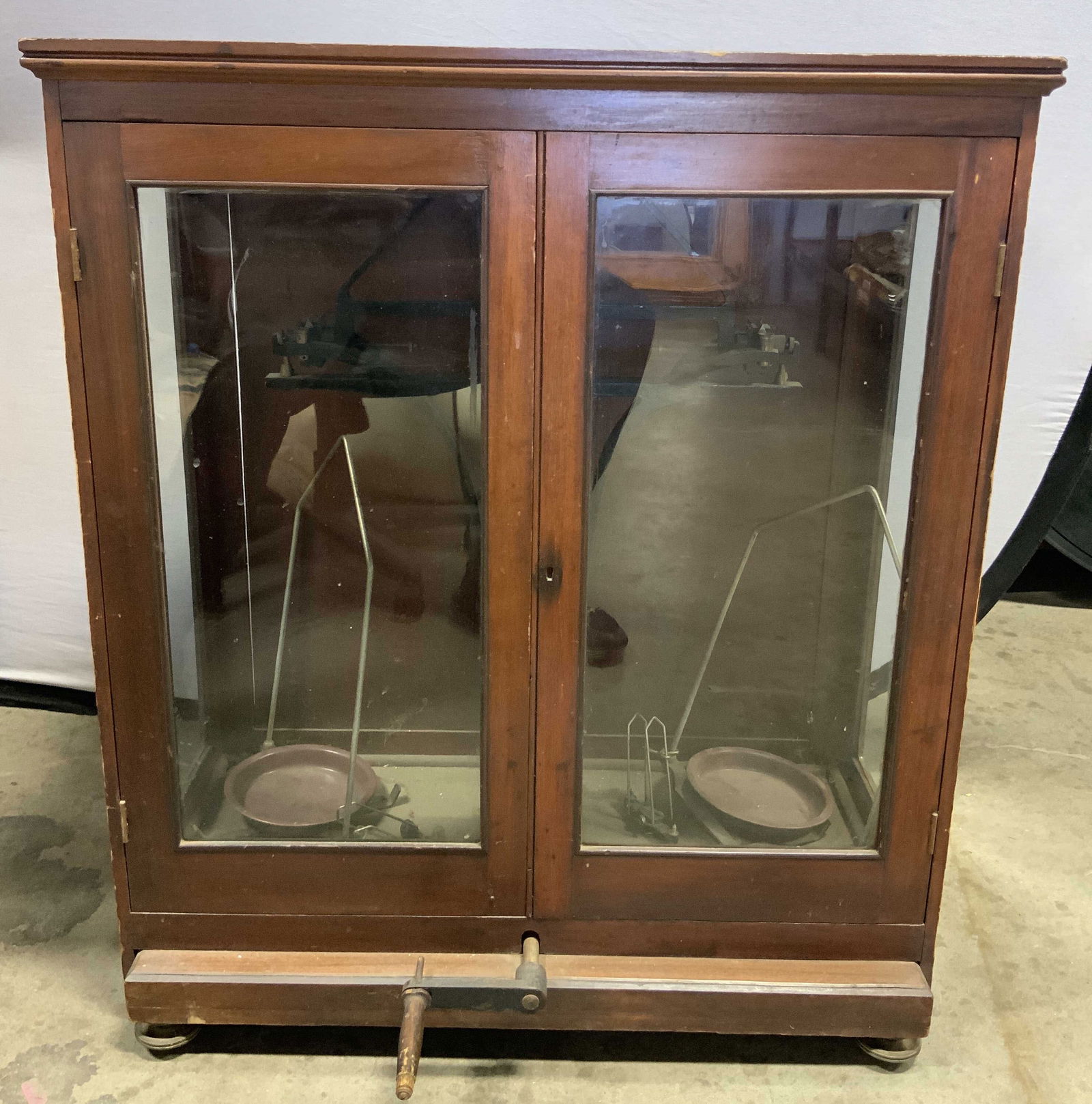 Antique Wooden Scale Cabinet W Crank: Scale cabinet appears to be antique possibly vintage. Piece has 2 windowed doors. Interior has scale, front of piece has crank with wooden handle. Piece measures approximately 33.5 inches tall 29 inch