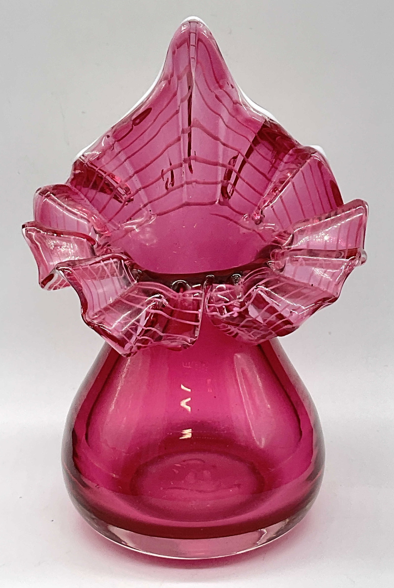 Jack in the Pulpit Ruffled Rim Cranberry Glass Vase: Jack in the Pulpit Ruffled White Ribbon Cranberry Red Glass Vase. Pontil to the underside. Measures approx. 7.5H x 5W in. Surface wear consistent with age, use, and exposure. Bubbles to glass. Chippin