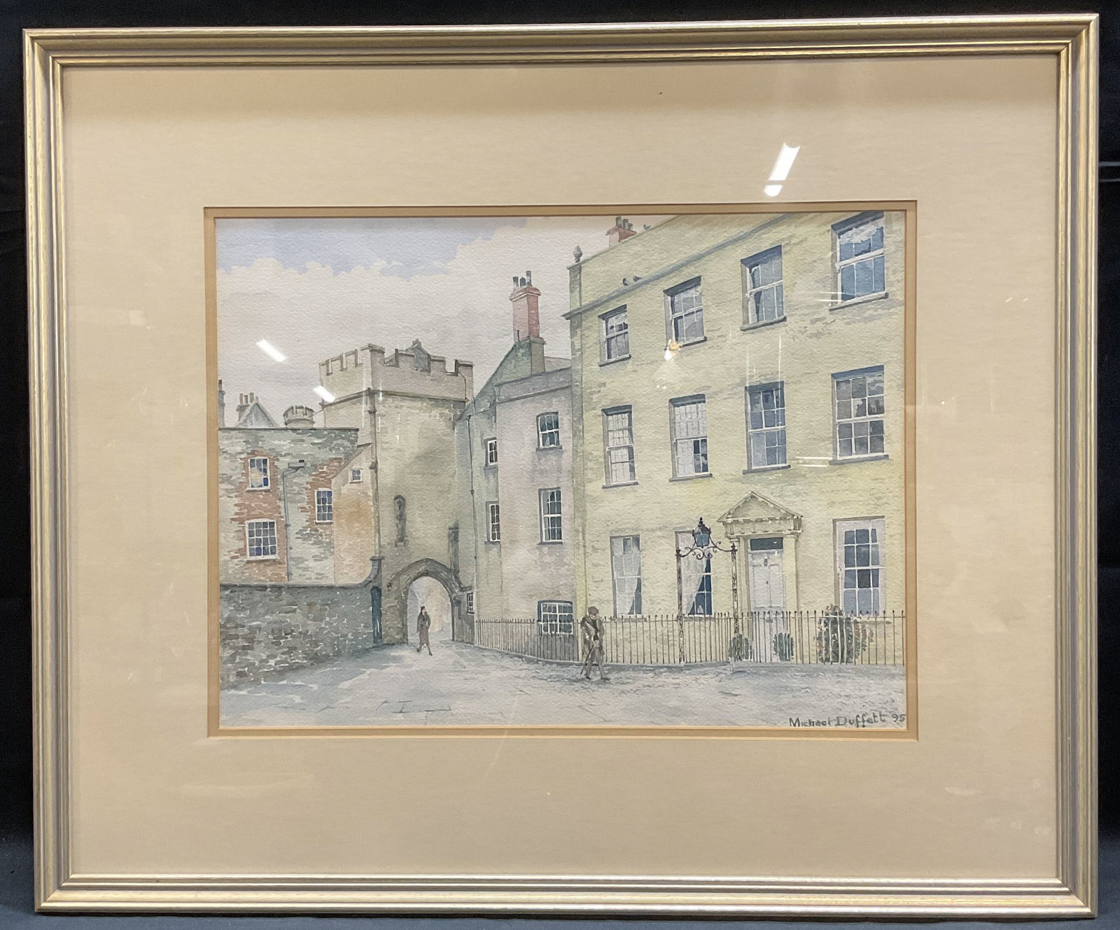 Michael Duffet Street Scene Watercolor Painting: Framed and signed watercolor painting on paper by Michael Duffet. Titled Penniless Porch By The Cathedral, Wells, Somerset. English street scene with building and figures. Signed on lower right and da