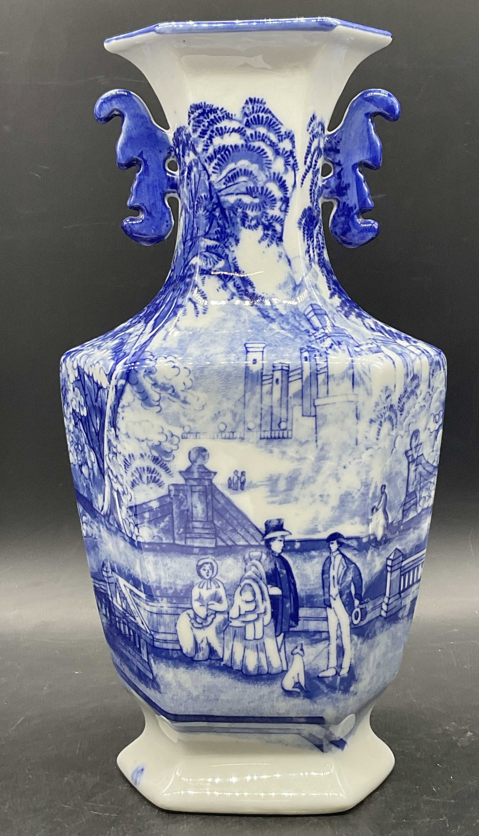 Vintage Trademarked Blue & White Ironstone Vase: Vintage Trademarked Blue & White Ironstone Vase. Figural motif to the obverse and reverse. Underside trademarked. Measures approx. 12H x 6W in. Surface wear consistent with age, use, and exposure. Pit