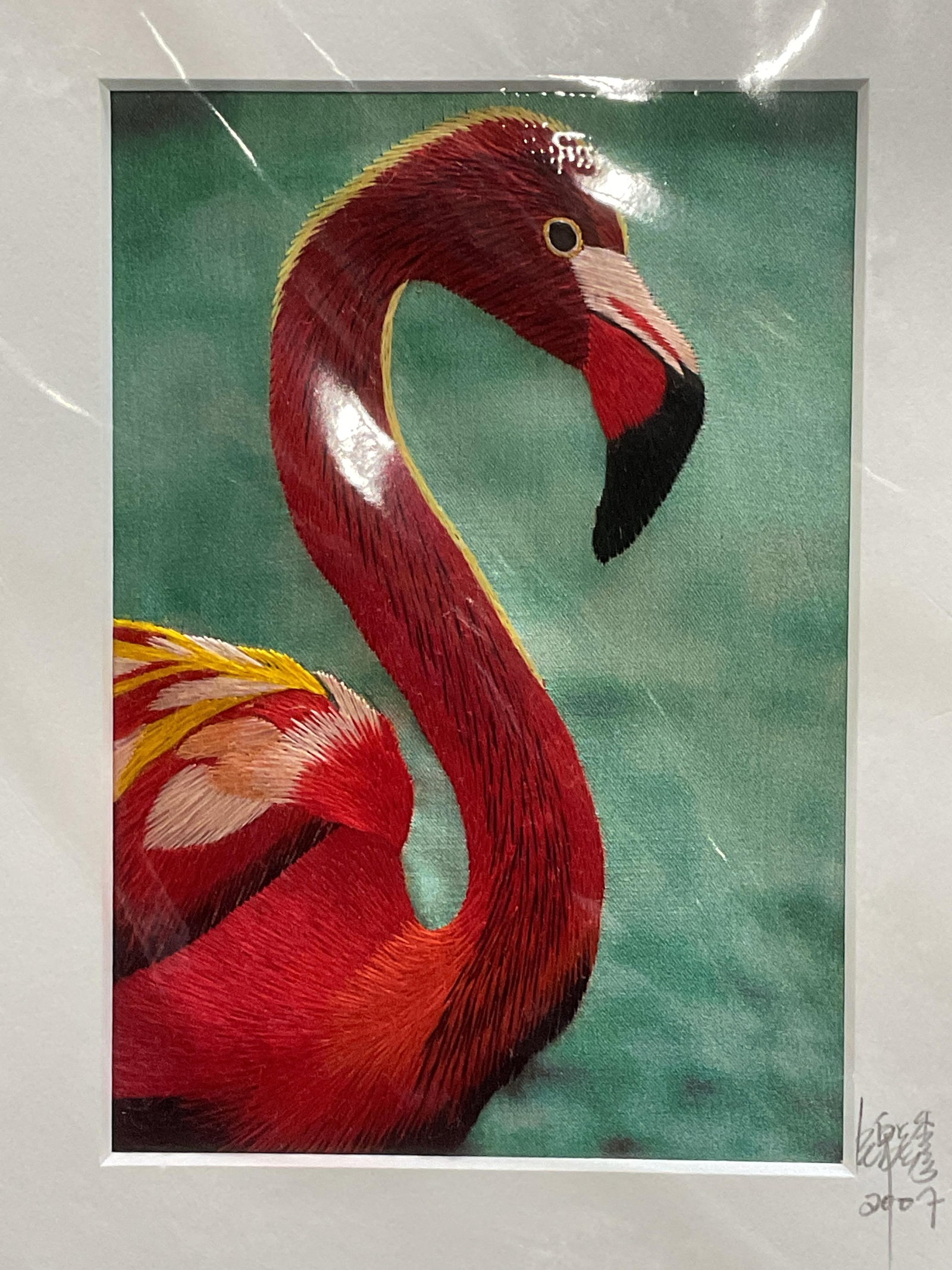 Embroidery Wonders Flamingo Silk Textile Art 2007: Matted textile panel by Embroidery Wonders. Signed on mat and dated 2007. Flamingo in pink on blue background. All silk. Hand sewn embroidered textile. In protective plastic, not viewed out of plastic