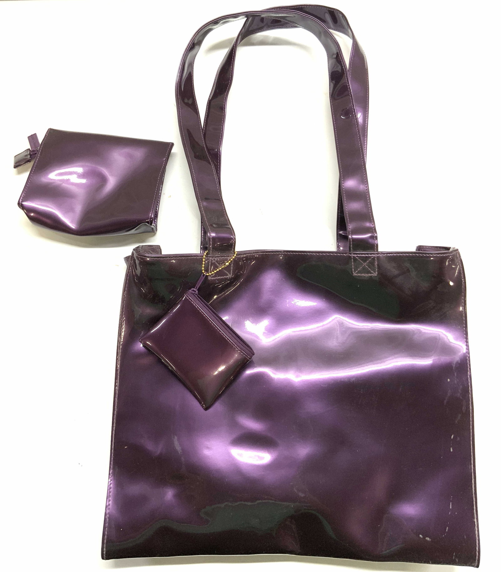 Estee LAUDER Patent Leather Purple Purse Set: Zipper pulls are trademarked Estee LAUDER. Lot includes 1 tote bag, 1 clutch and 1 coin purse. Each piece is purple toned patent leather. Interior of tote has 1 open pocket. Tote measures approximatel