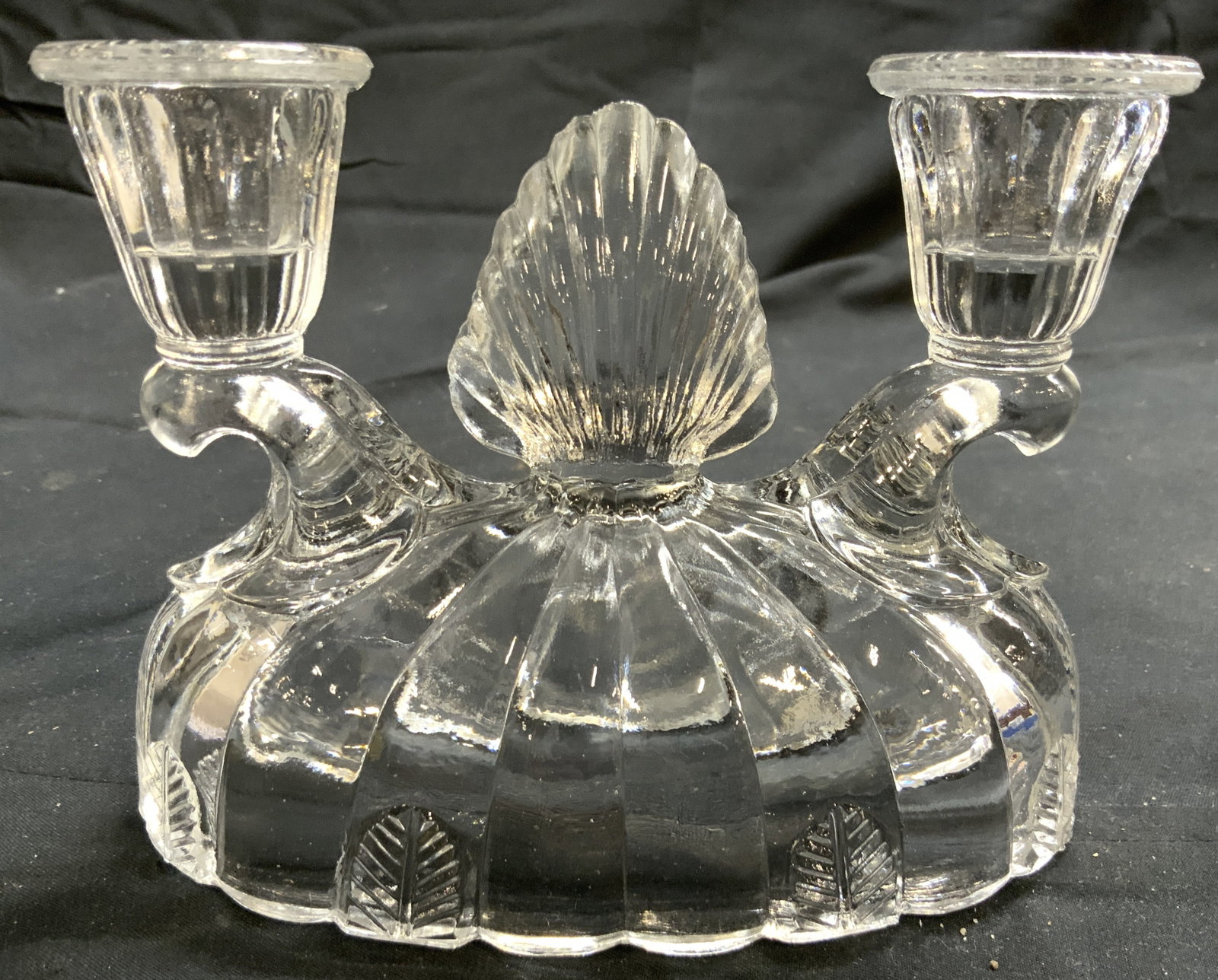 Scalloped 2 Arm Art Glass Candelabra: Candelabra is glass. Piece has 2 arms. Candelabra has scalloped base. Piece has some areas of leaf form relief detail. Piece measures approximately 5.75 inches wide 4.5 inches tall 3 inches deep. Cand