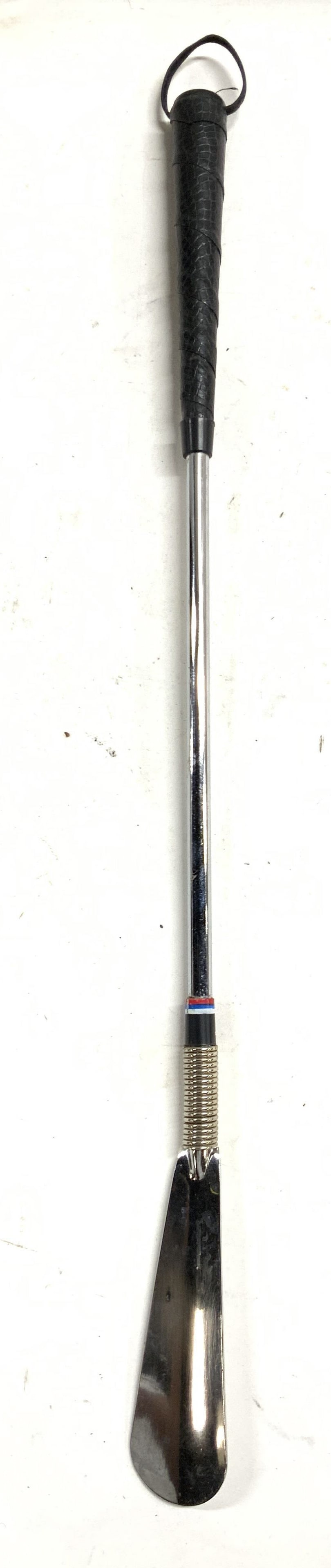 Stainless Steel Shoe Horn W Leatherette Grip: Show horn is stainless steel. Piece is black and silver toned. Show horn has black toned leatherette handle and loop at end to hang. Piece measures approximately 23 inches tall 1.5 inches wide. Stainl